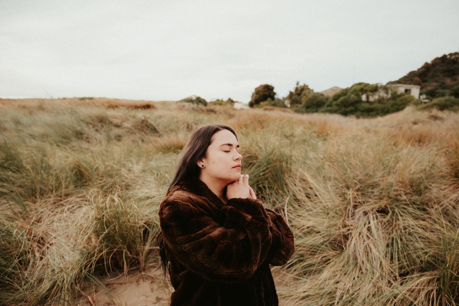 Candid moments captured in golden hour among windswept coastal grasses.
