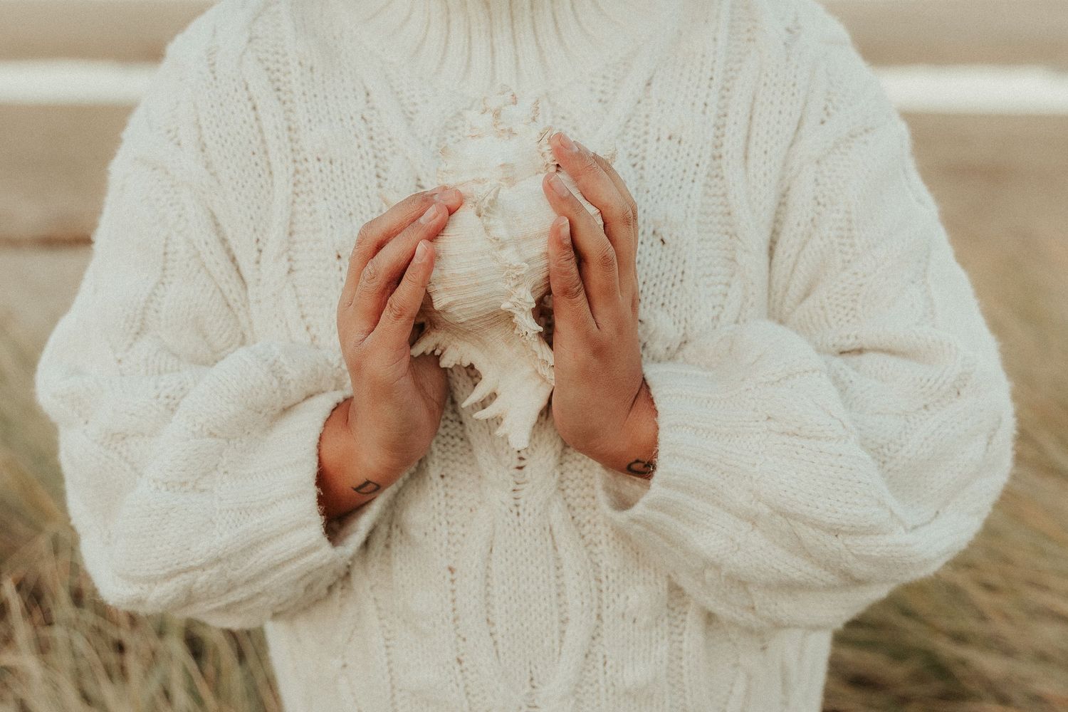 Close-up shots of hands gesturing while wearing a chunky cream-colored knit sweater.