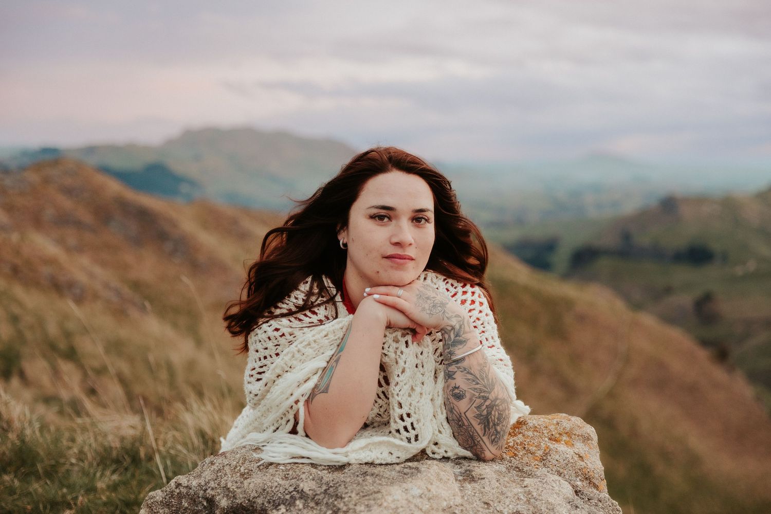 Dreamy outdoor portrait with mountain landscape in soft evening light.