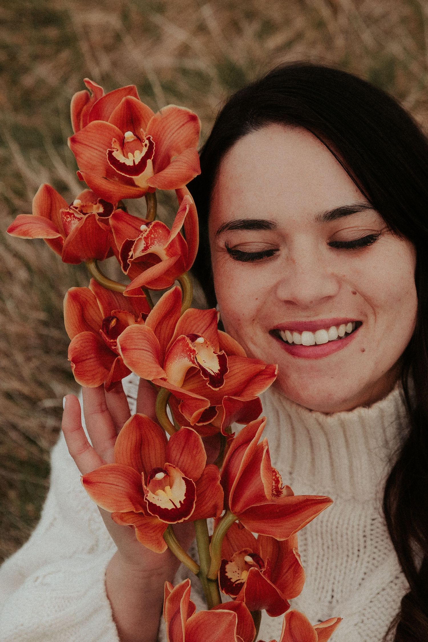 Close-up portrait with vibrant coral orchids against natural outdoor setting.