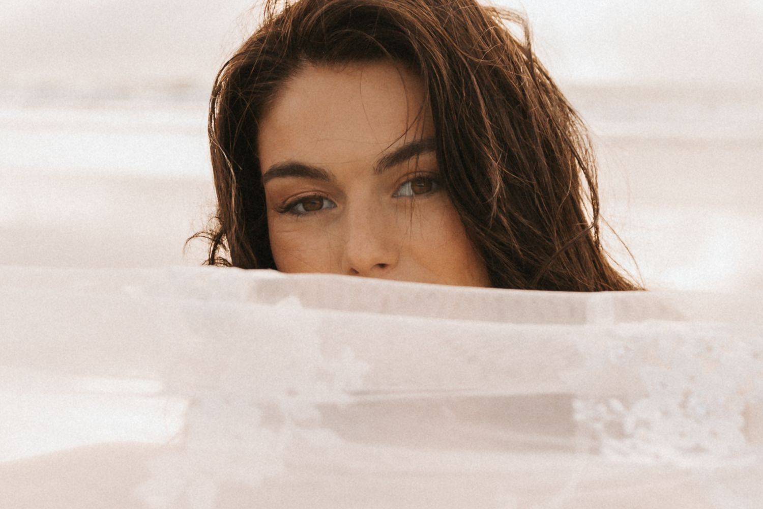 Soft sepia-toned beach portrait with gentle waves and dreamy atmosphere.