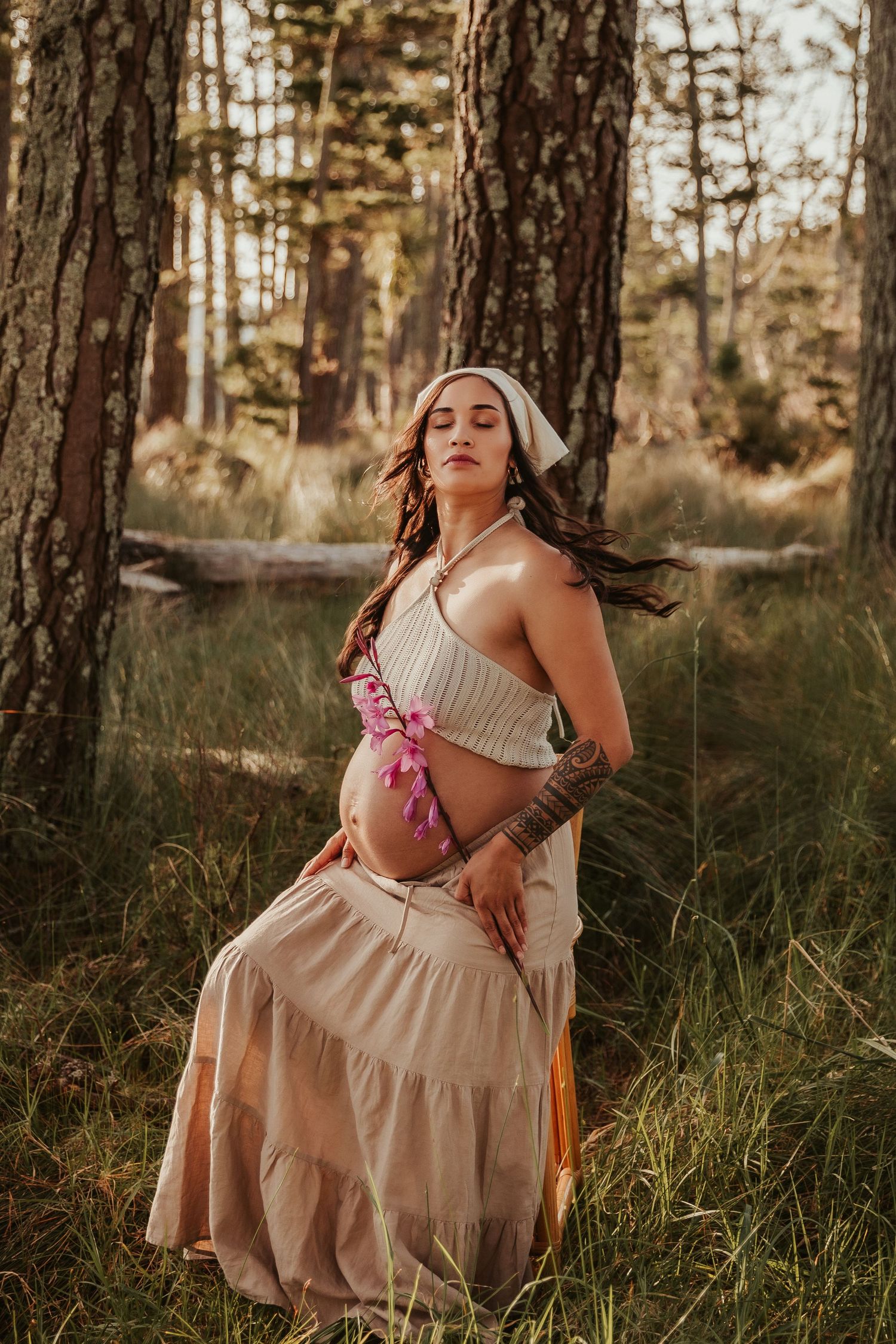 Figure in neutral-toned dress creates elegant poses in a sun-dappled forest setting.