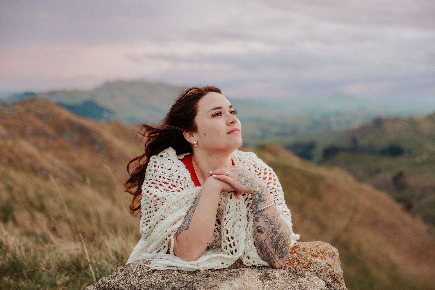 Artistic portrait against rolling hills and mountains during golden hour.