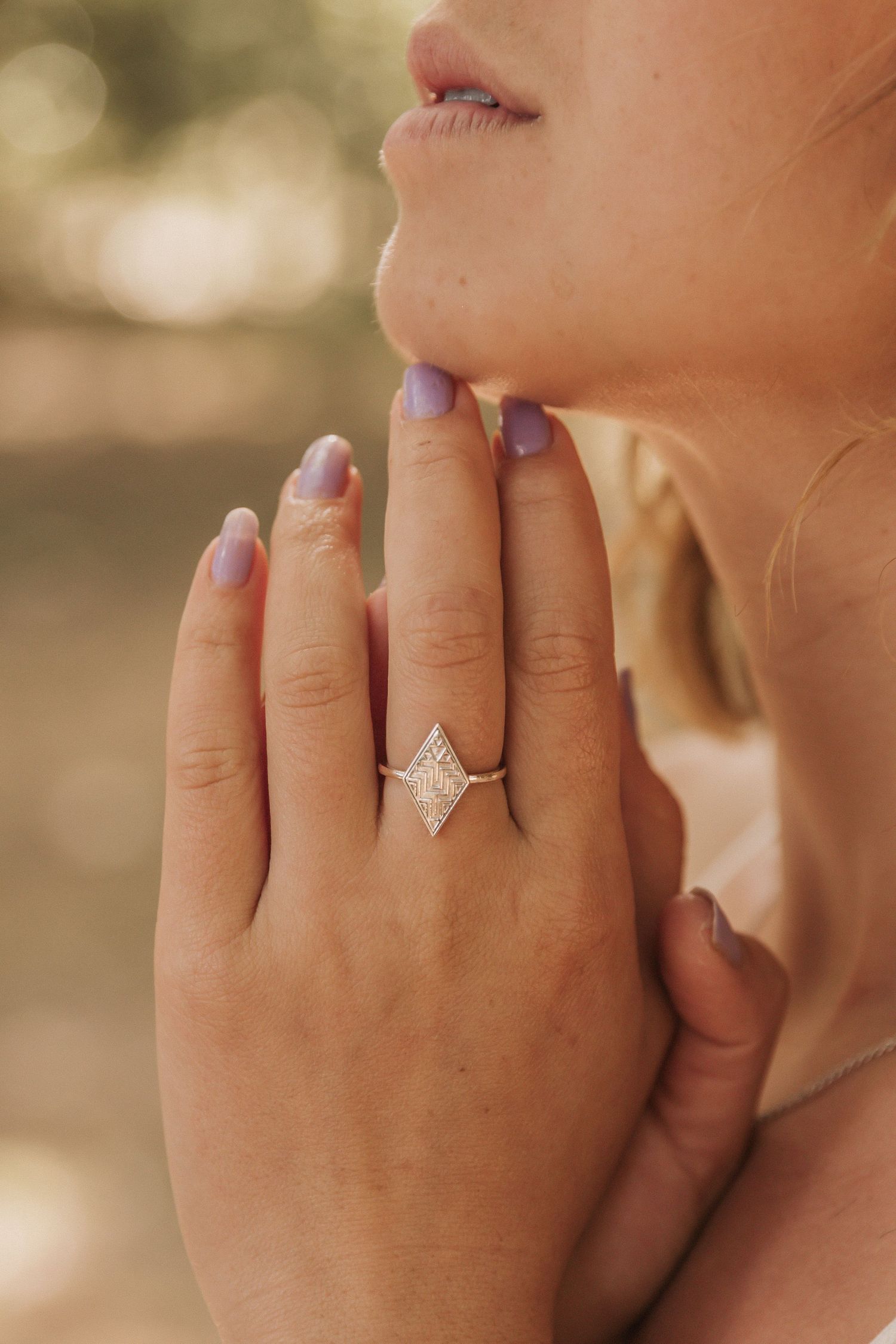 Close-up view of a sparkling pear-shaped diamond engagement ring on a woman's hand with a soft blurred background.