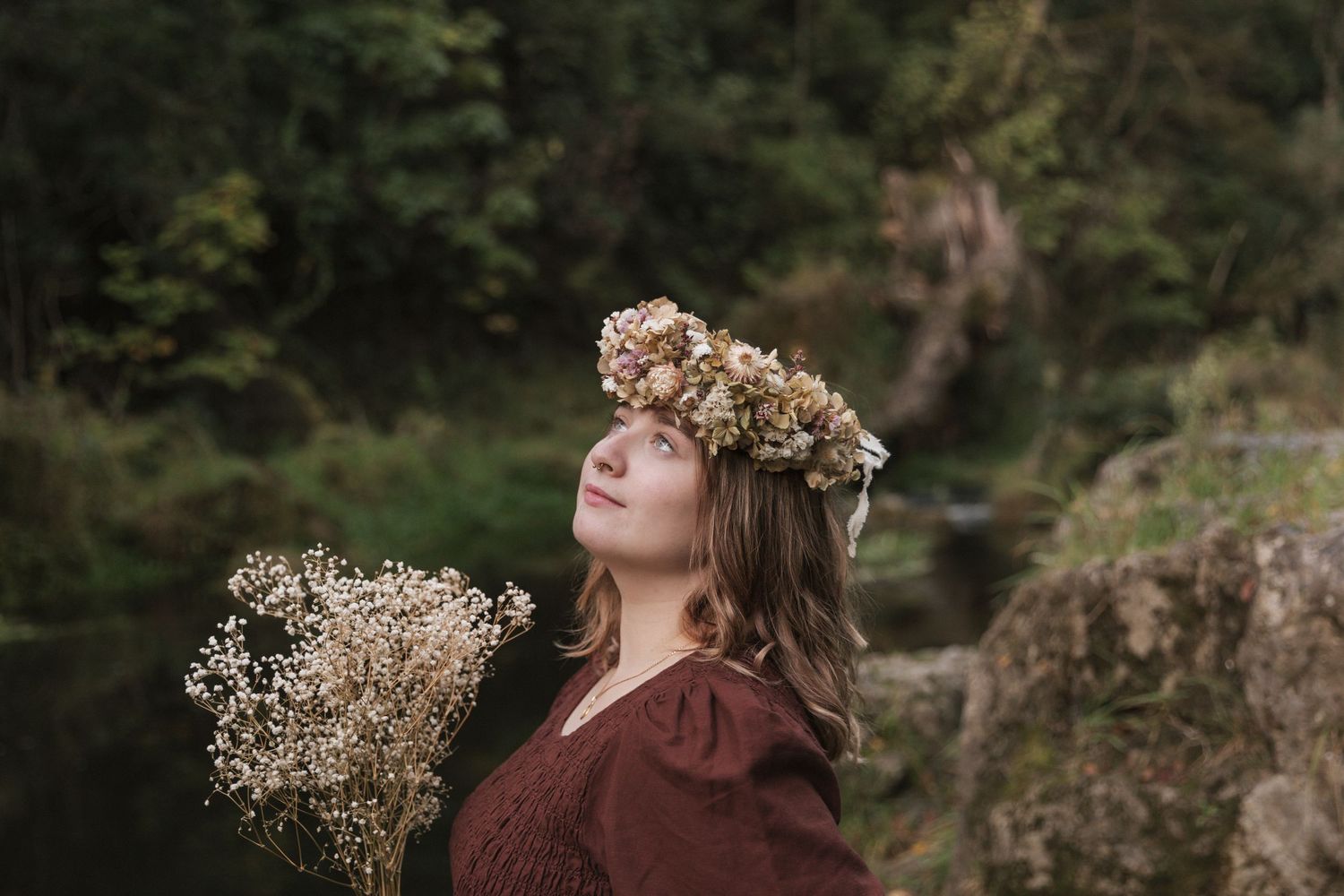 A dreamy portrait with a floral crown and dried flowers against a forest backdrop.