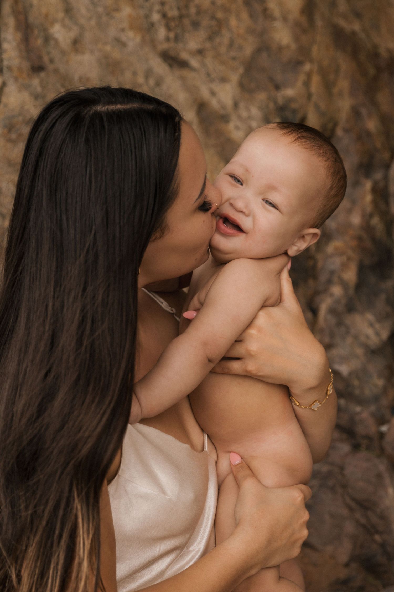 Intimate portrait session with gentle expressions against a natural stone backdrop.