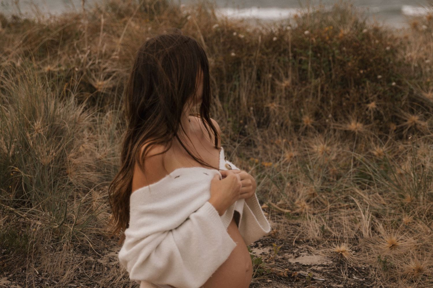 Artistic beach portrait session with white fabric in natural lighting.