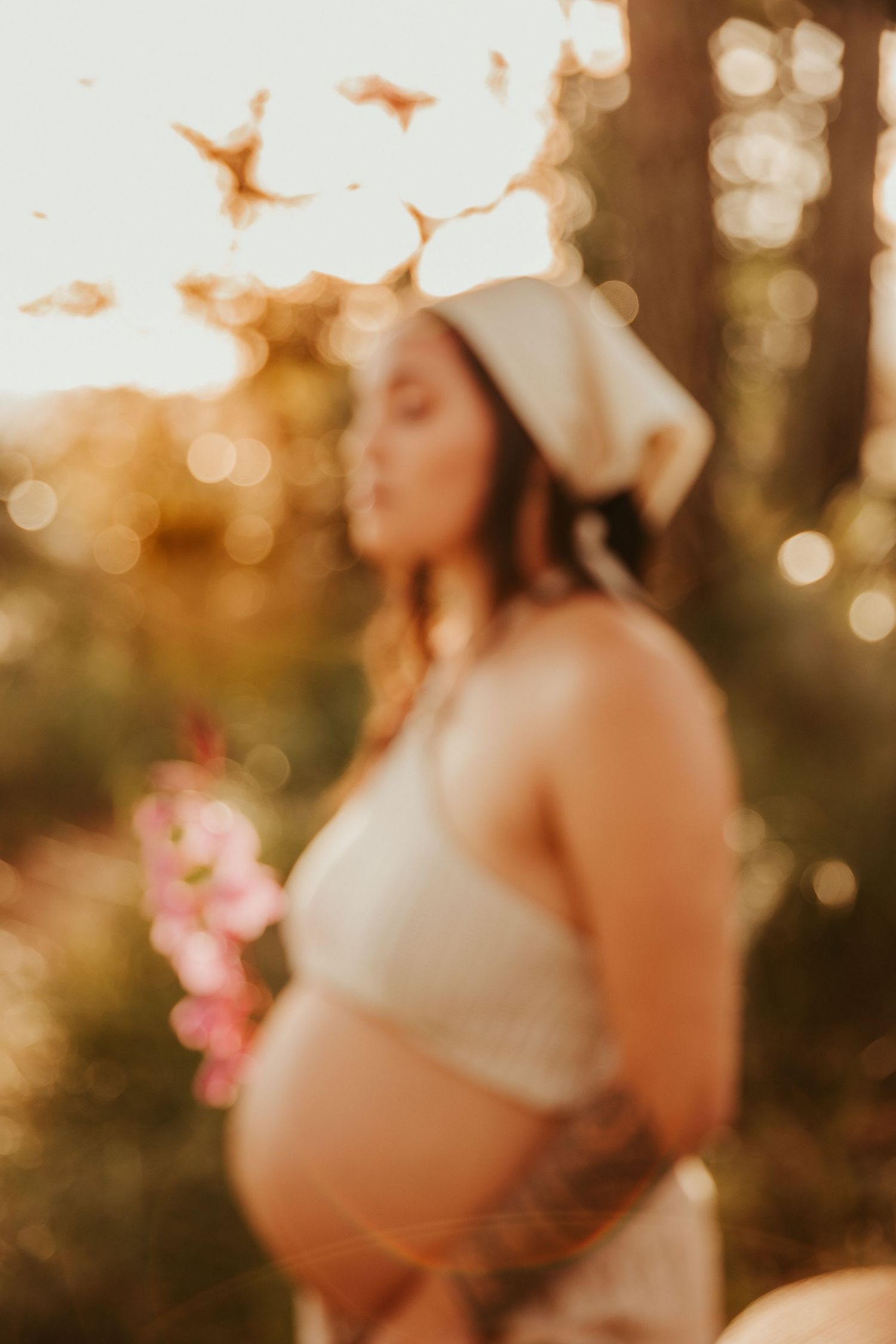 Dreamy outdoor maternity portrait with golden sunset bokeh in background.