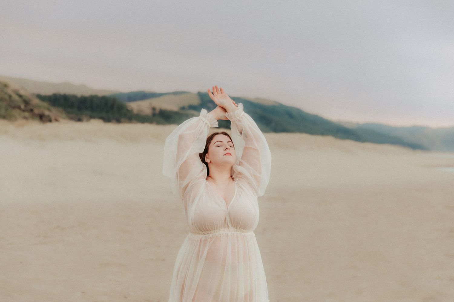 Dreamy beach portrait session featuring soft pink dress against coastal landscape.