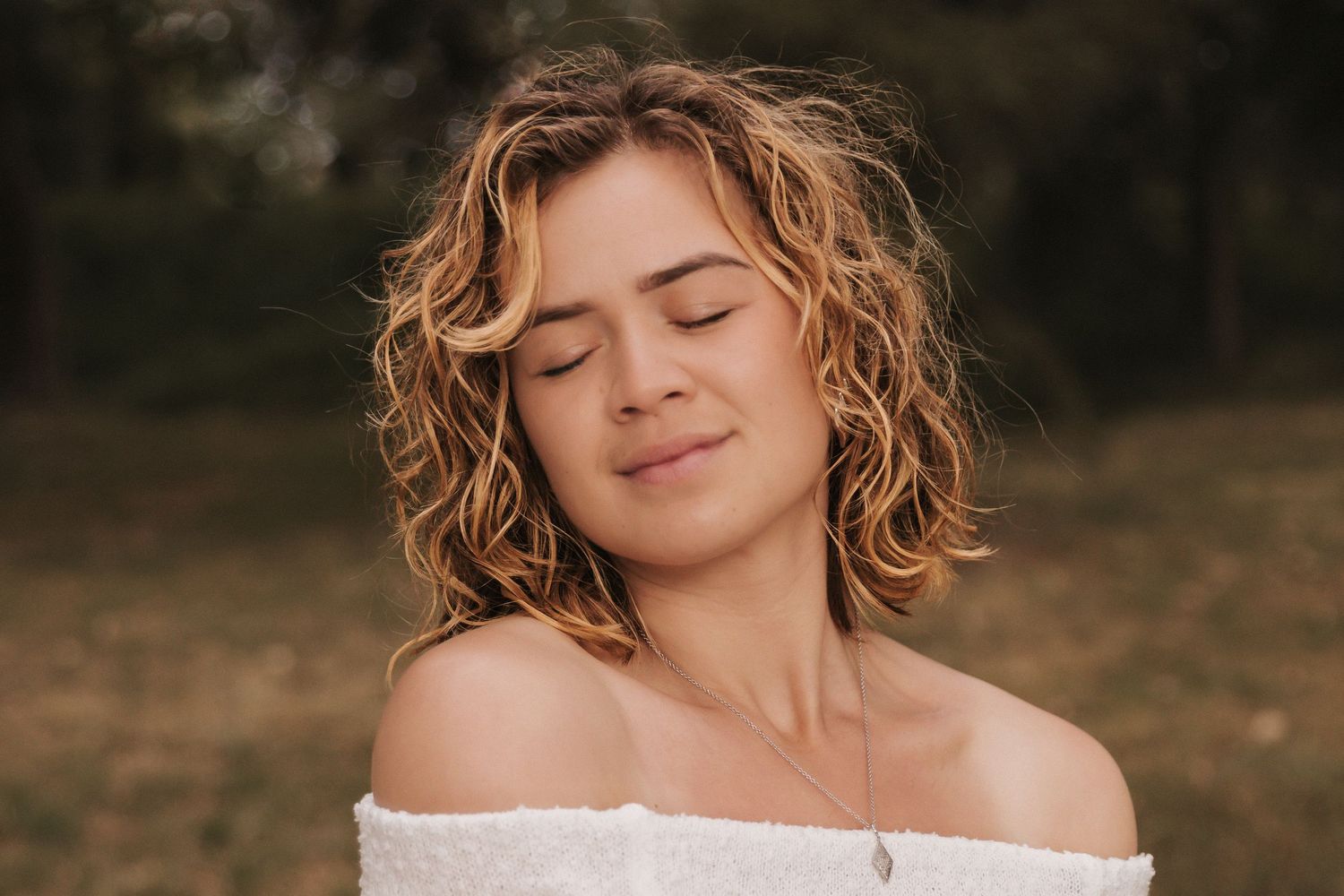 Artistic portrait sequence with eyes closed in white outfit against forest background.