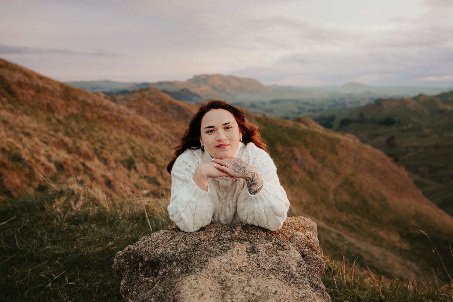 Peaceful portrait on rocky terrain with mountains stretching into the distance.