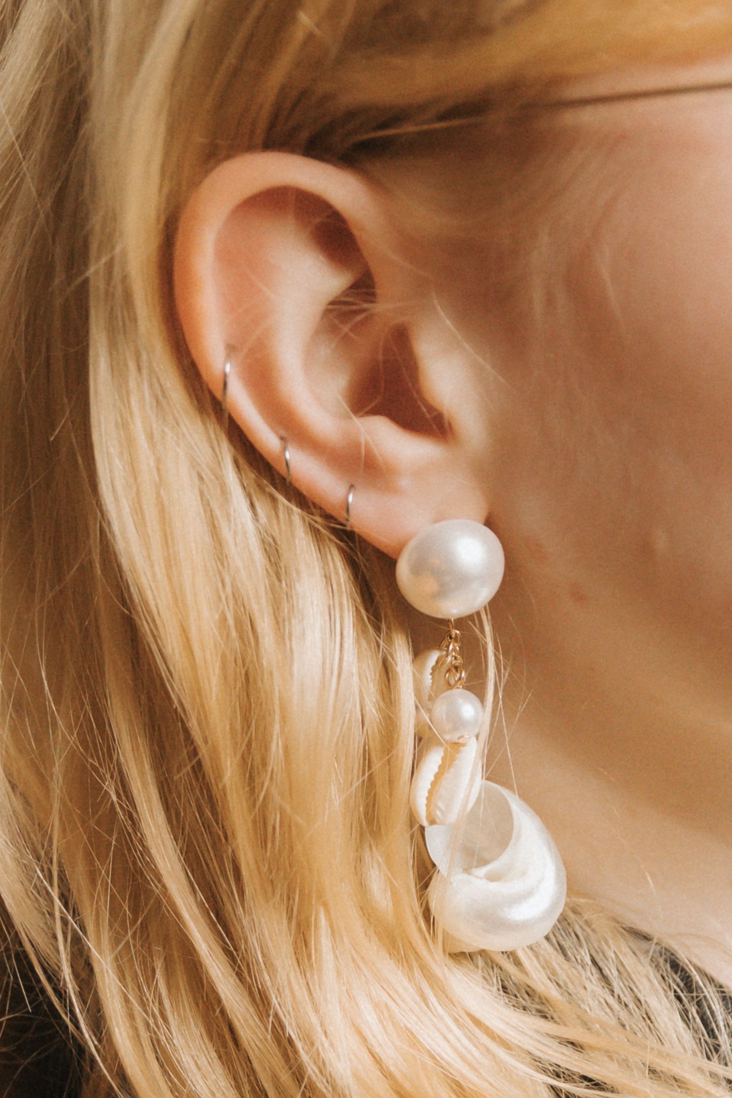 Close-up photos showing a pearl earring from different angles against blonde hair.