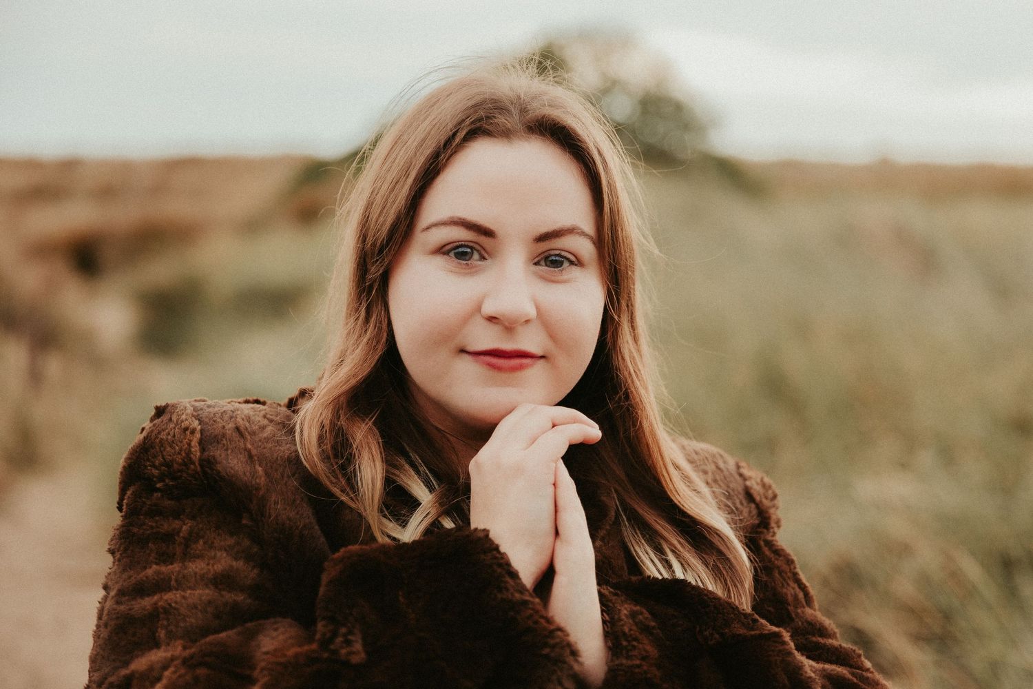 Natural outdoor portrait series with warm autumn tones in tall grass.
