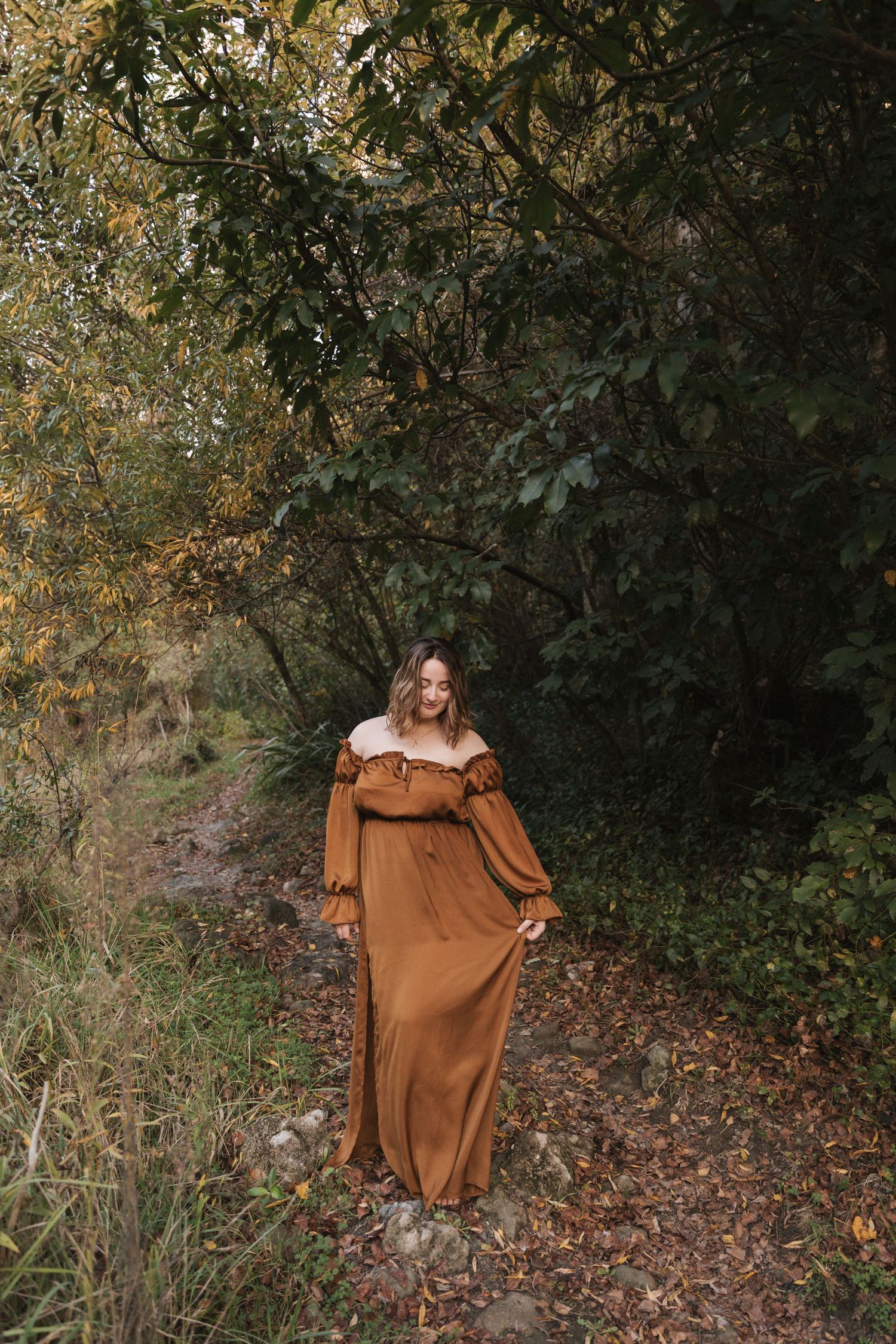 A brown vintage-style dress with ruffled details photographed against a dark forest backdrop.