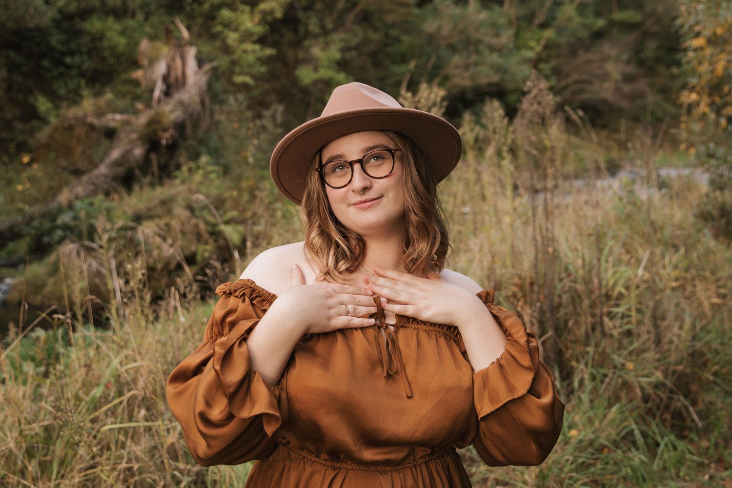 Vintage-inspired autumn fashion shoot with brown dress and wide-brimmed hat in tall grass.