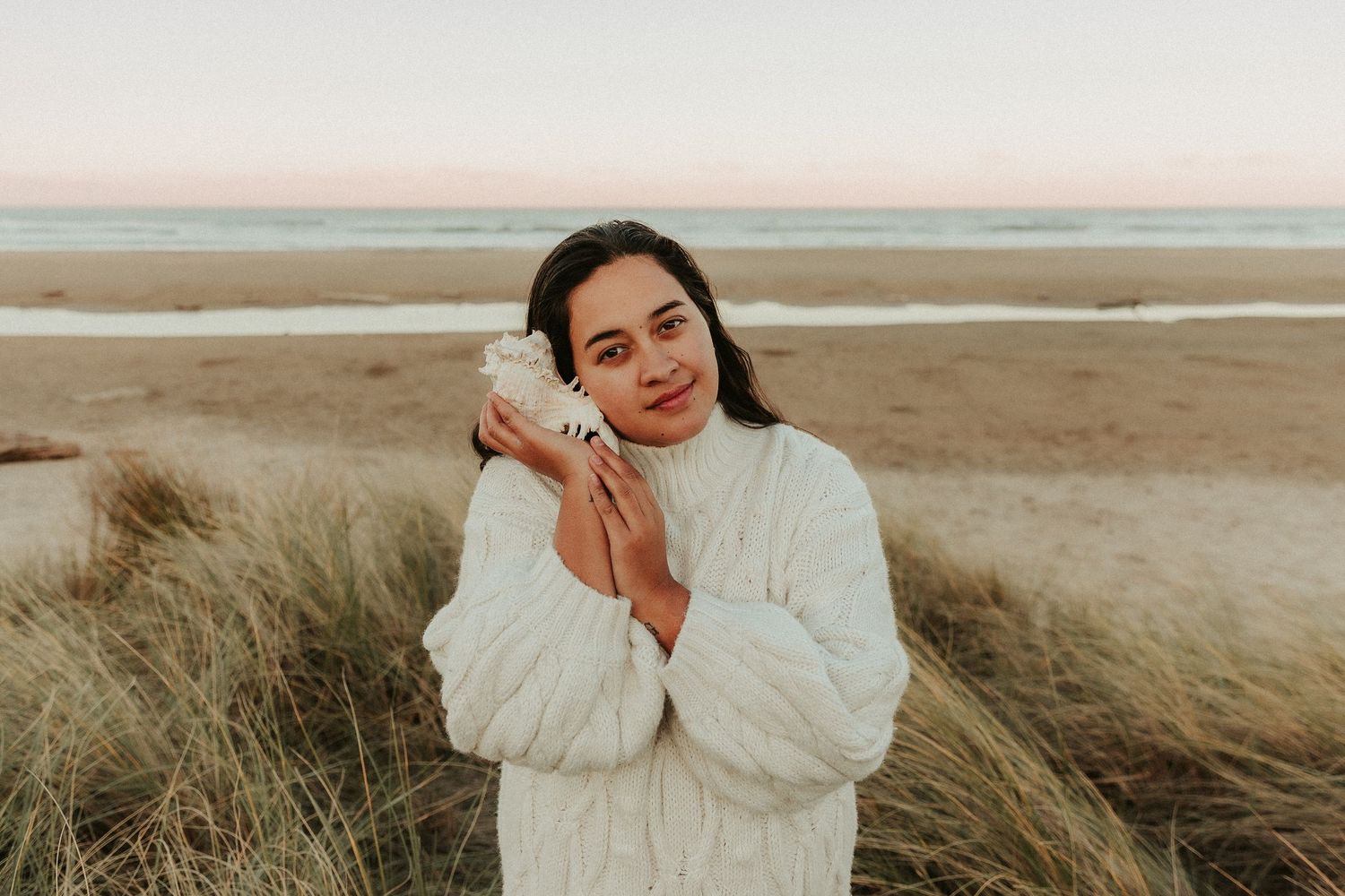 Serene coastal portrait with warm tones and flowing white clothing.