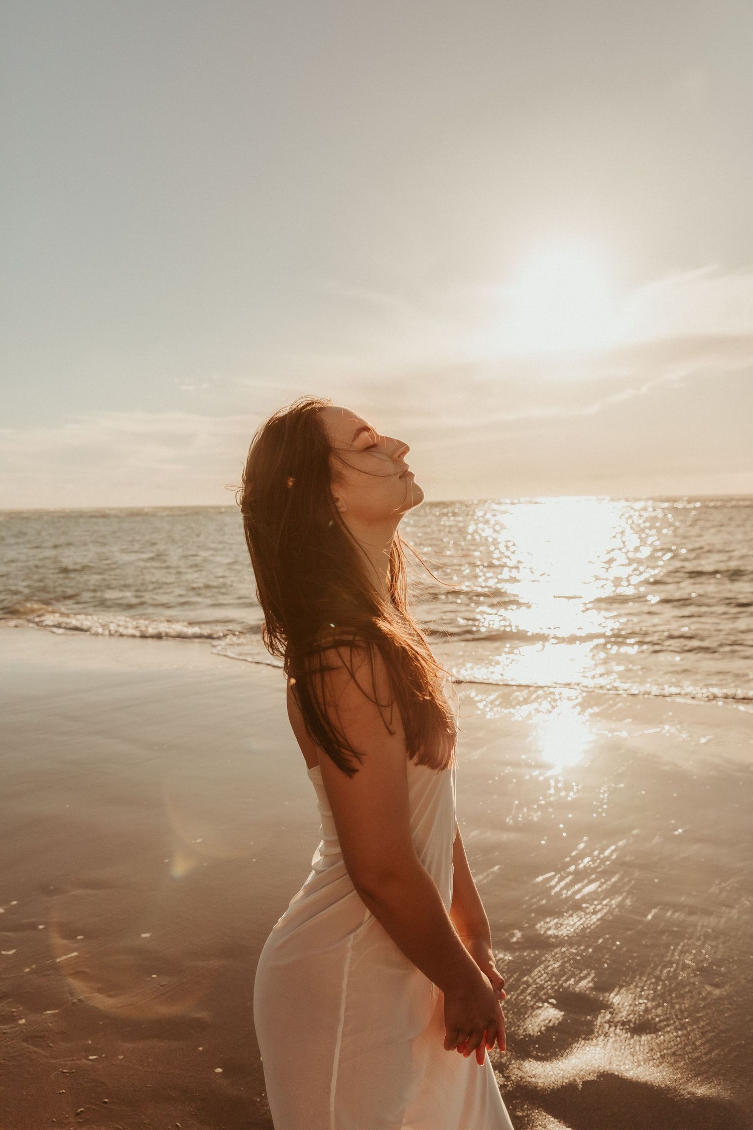 Silhouette against sparkling ocean waves during a sunset beach photoshoot.