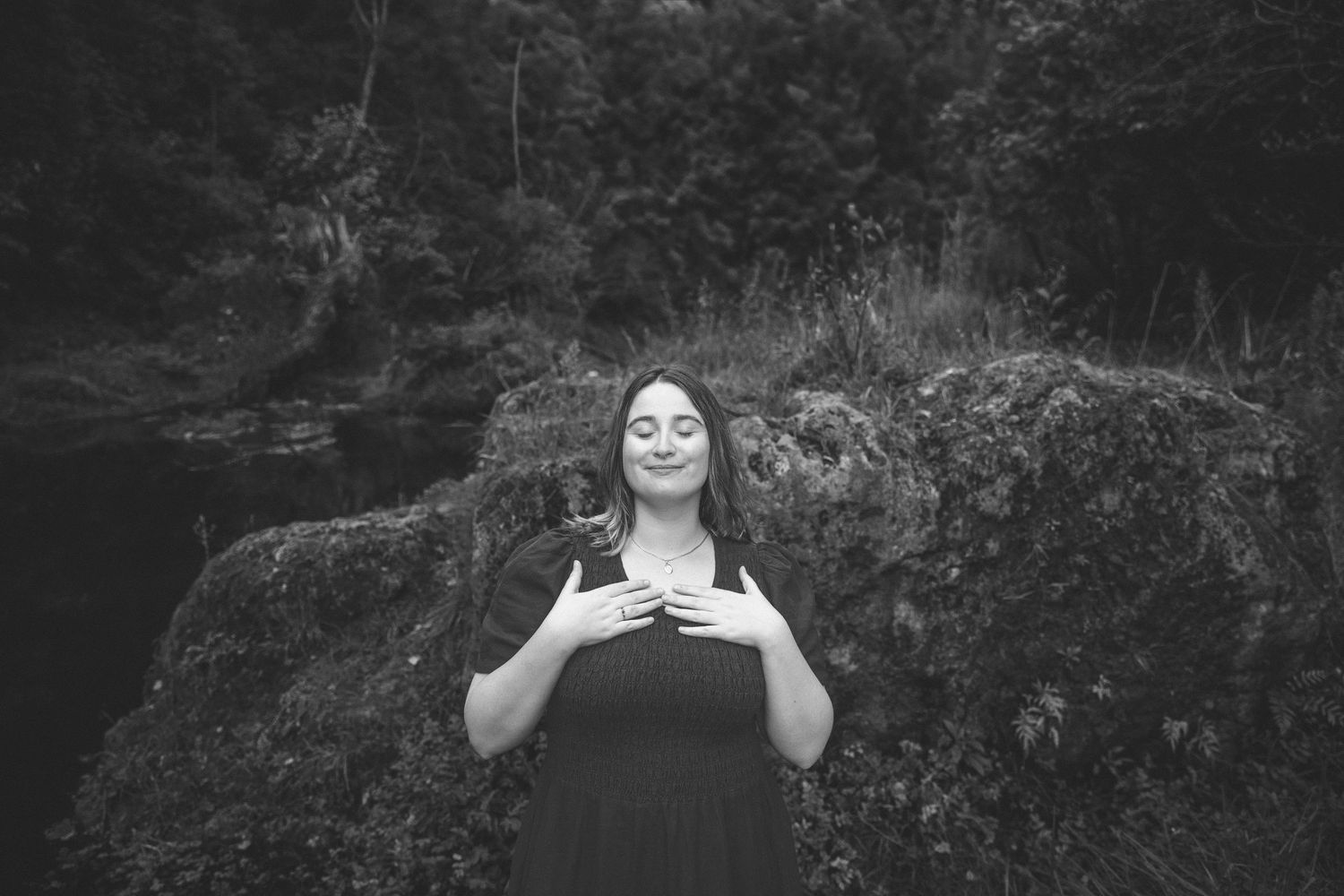 A black and white portrait capturing a serene moment against rocky natural scenery.