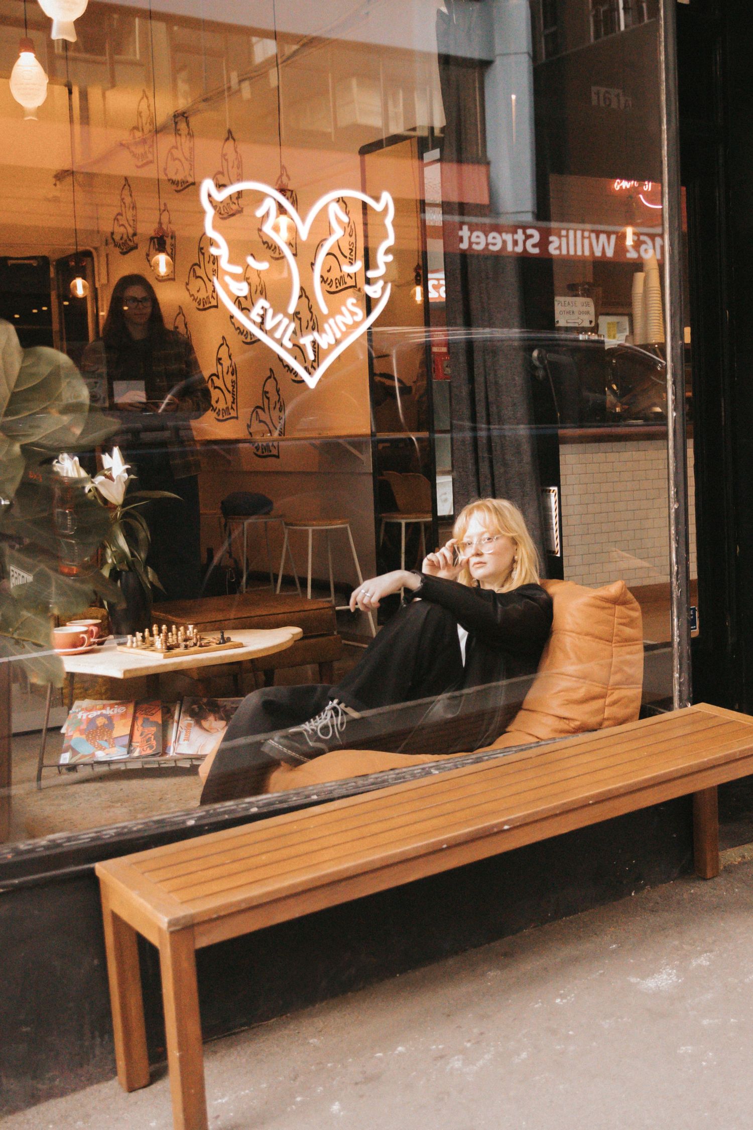 Storefront window display with a long wooden bench and illuminated heart-shaped neon signs glowing in warm light.
