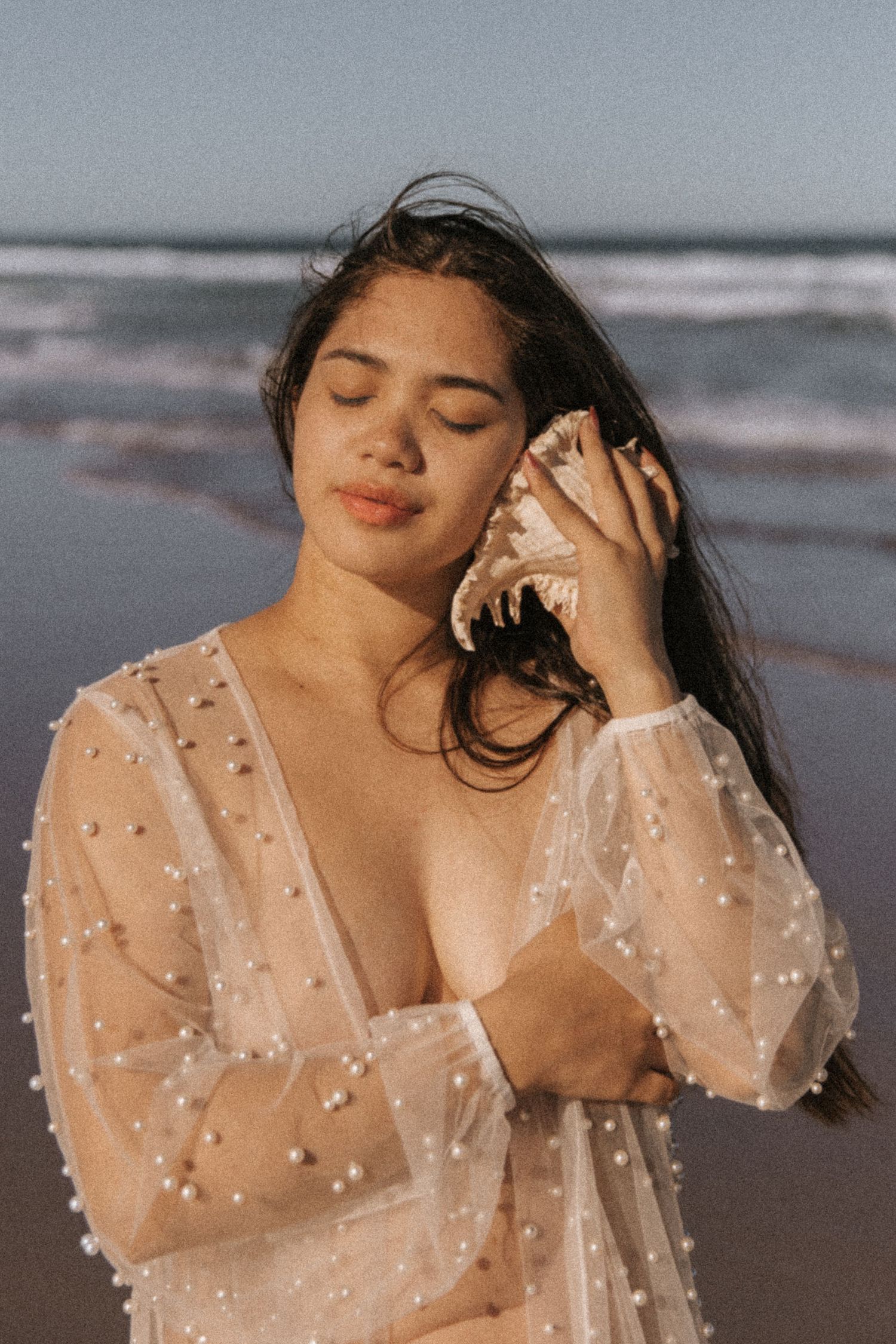 Romantic beach photography series with delicate pearl-adorned sheer fabric.