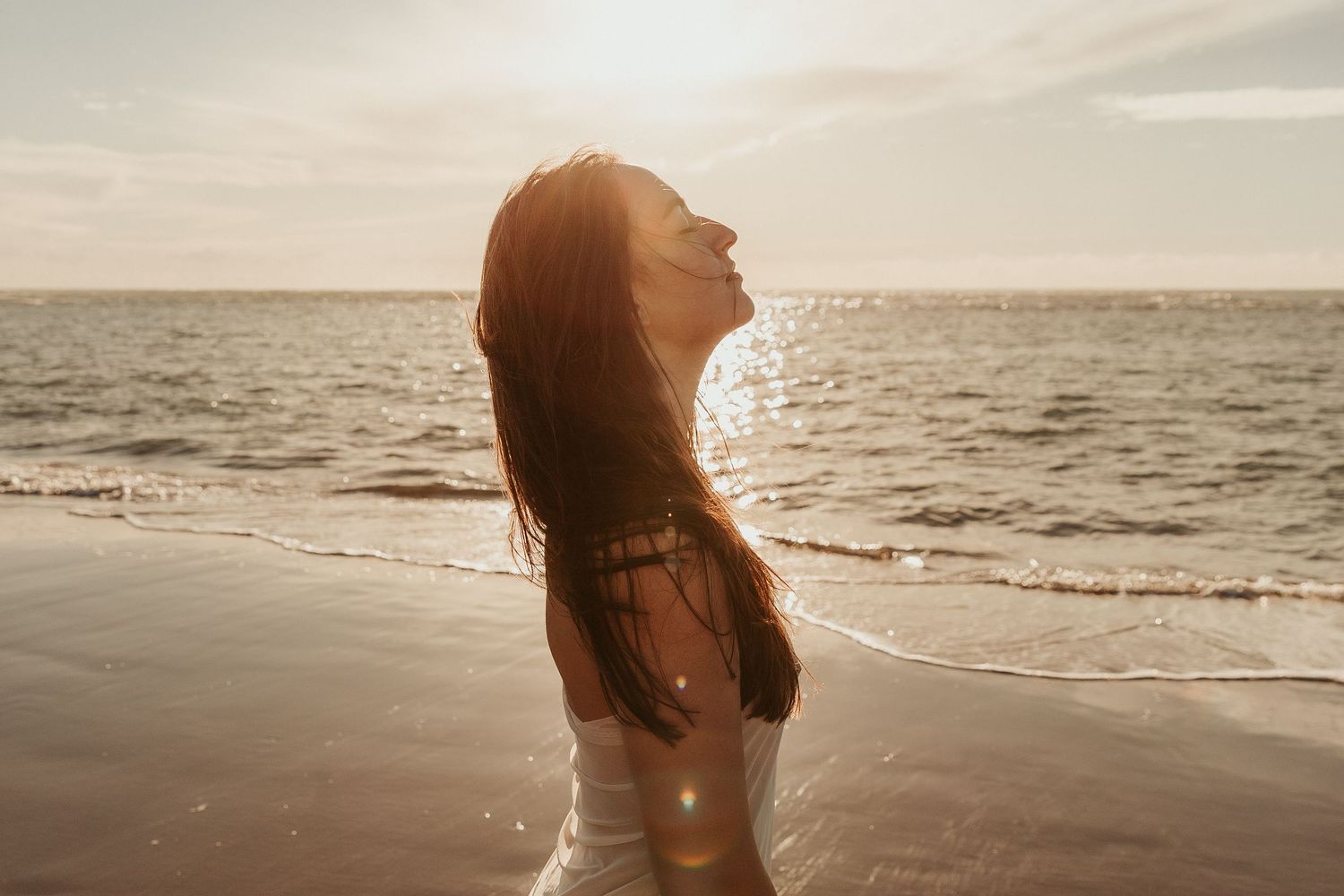 Artistic beach portrait with sunlight creating a warm golden glow.