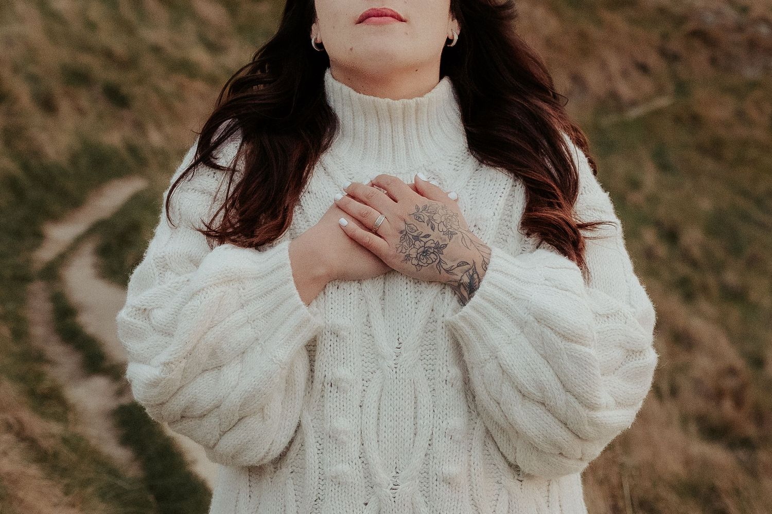 Person wearing white puff sleeve top poses against natural outdoor backdrop.