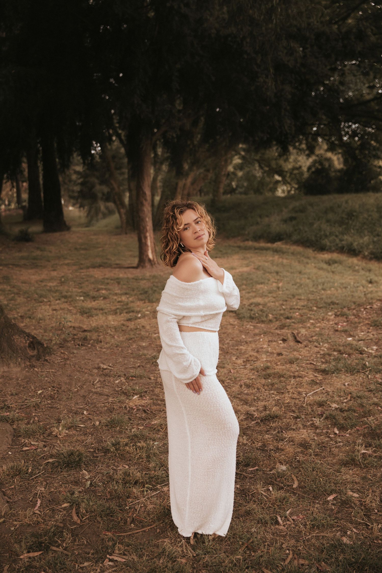 Ethereal portrait series in flowing white ensemble on rustic woodland hillside.