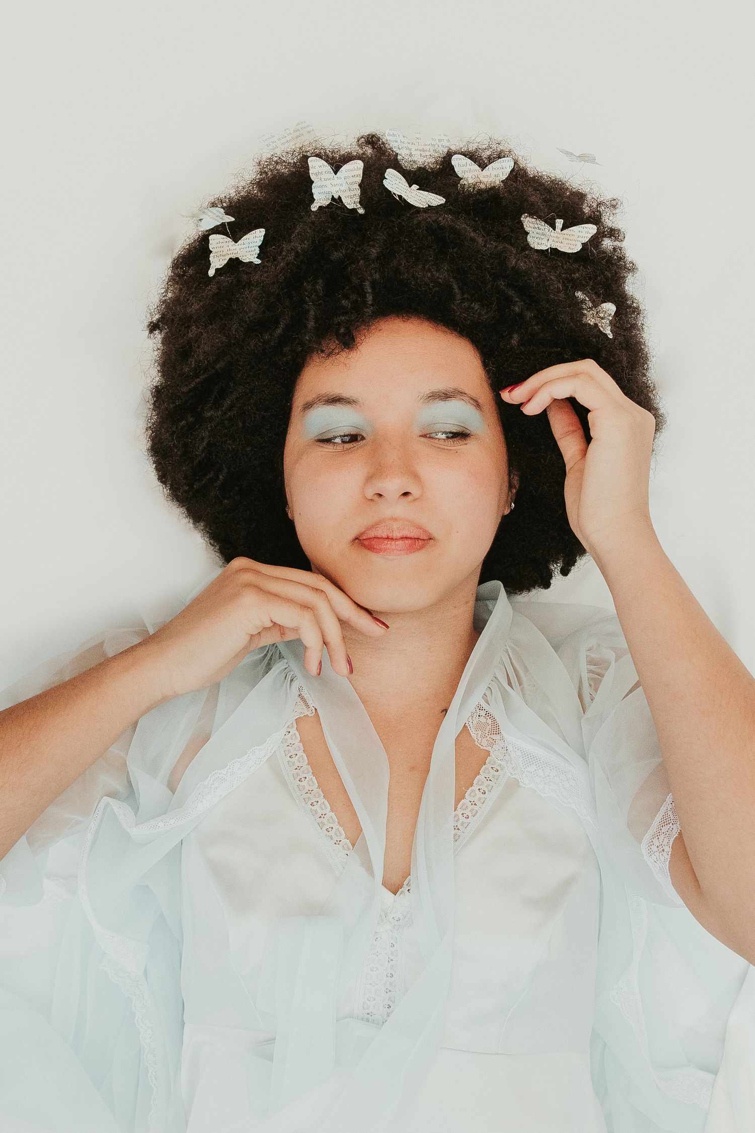 Ethereal portrait in white lace dress with butterflies in hair.