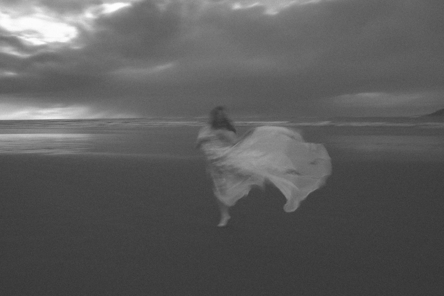 A dramatic black and white photo of a dress flowing in coastal winds.