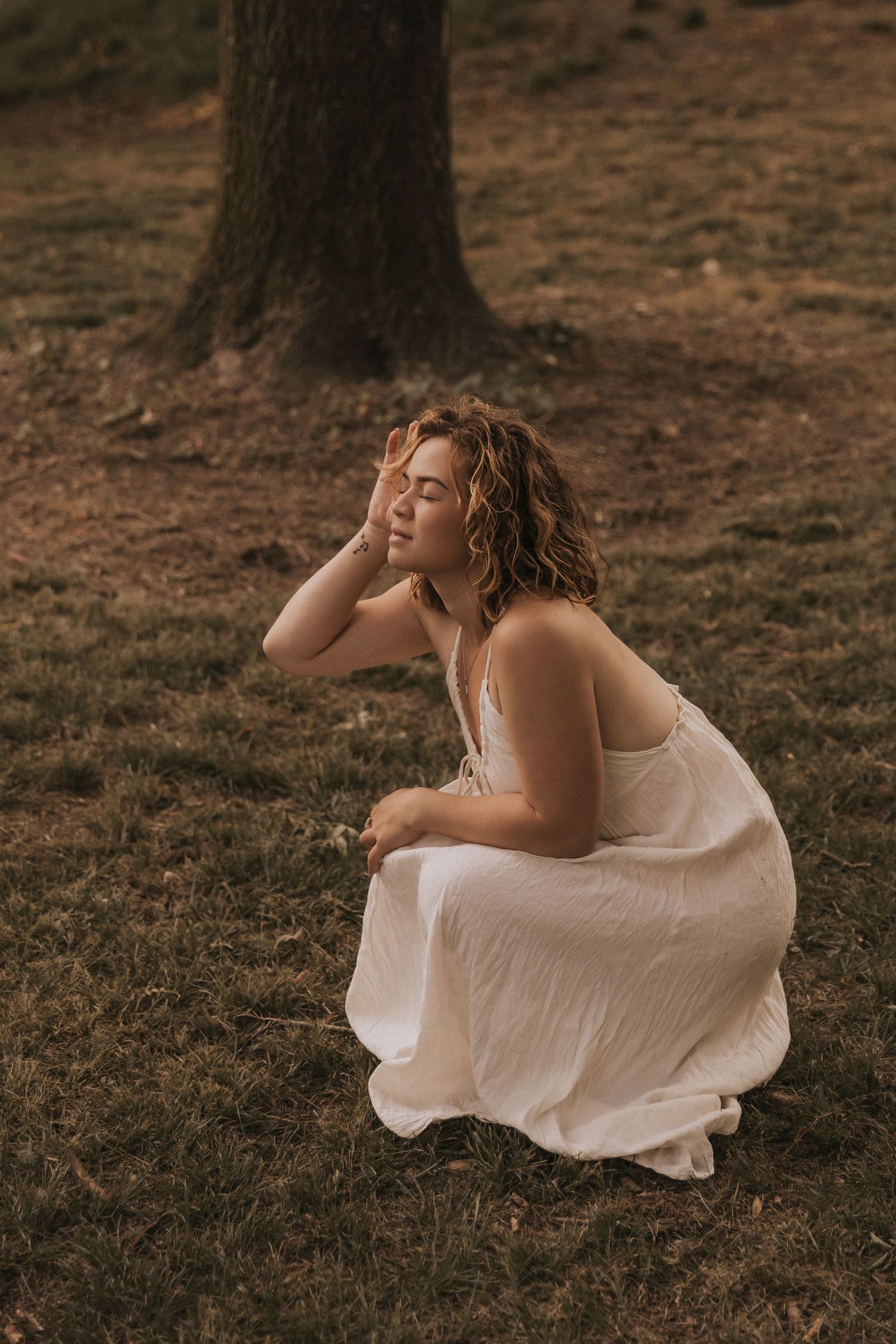 A contemplative moment captured in a white dress against a natural forest backdrop.