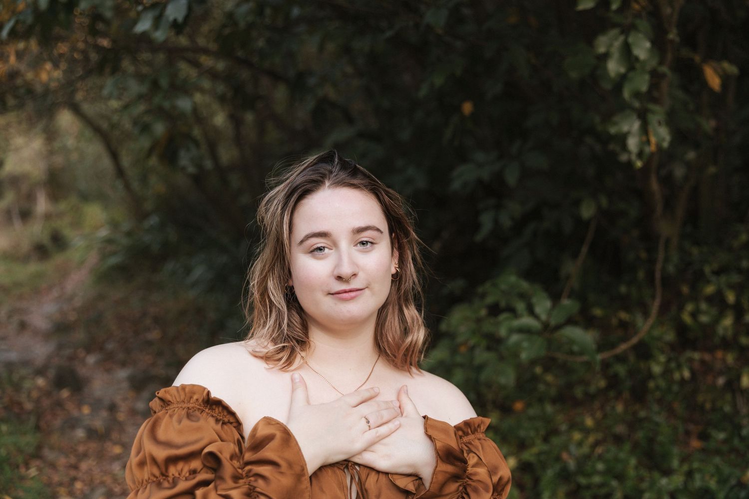Artistic portrait featuring a brown prairie-style dress with ruffle details in a forest setting.