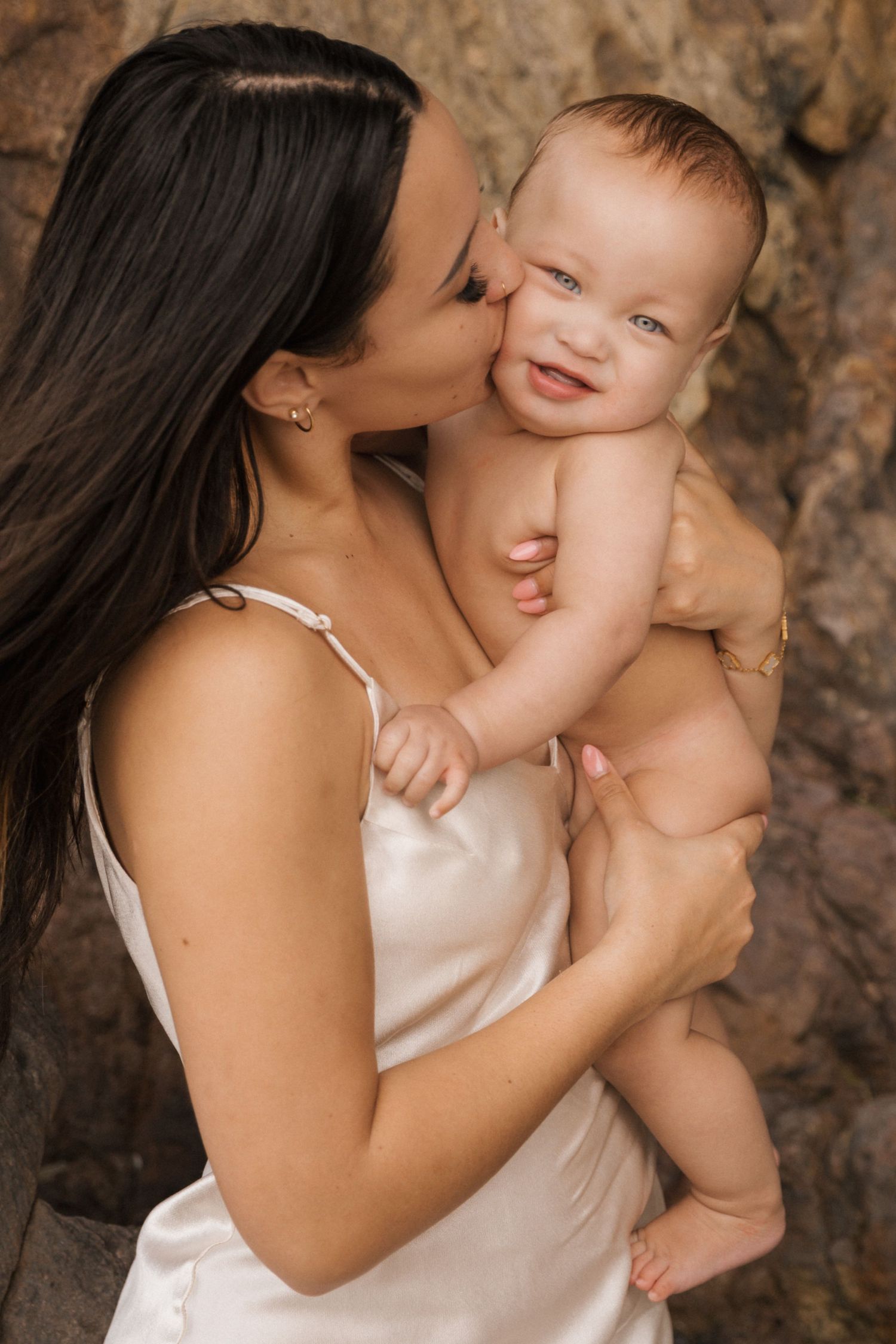 Tender moment captured in natural light against rocky cave walls.