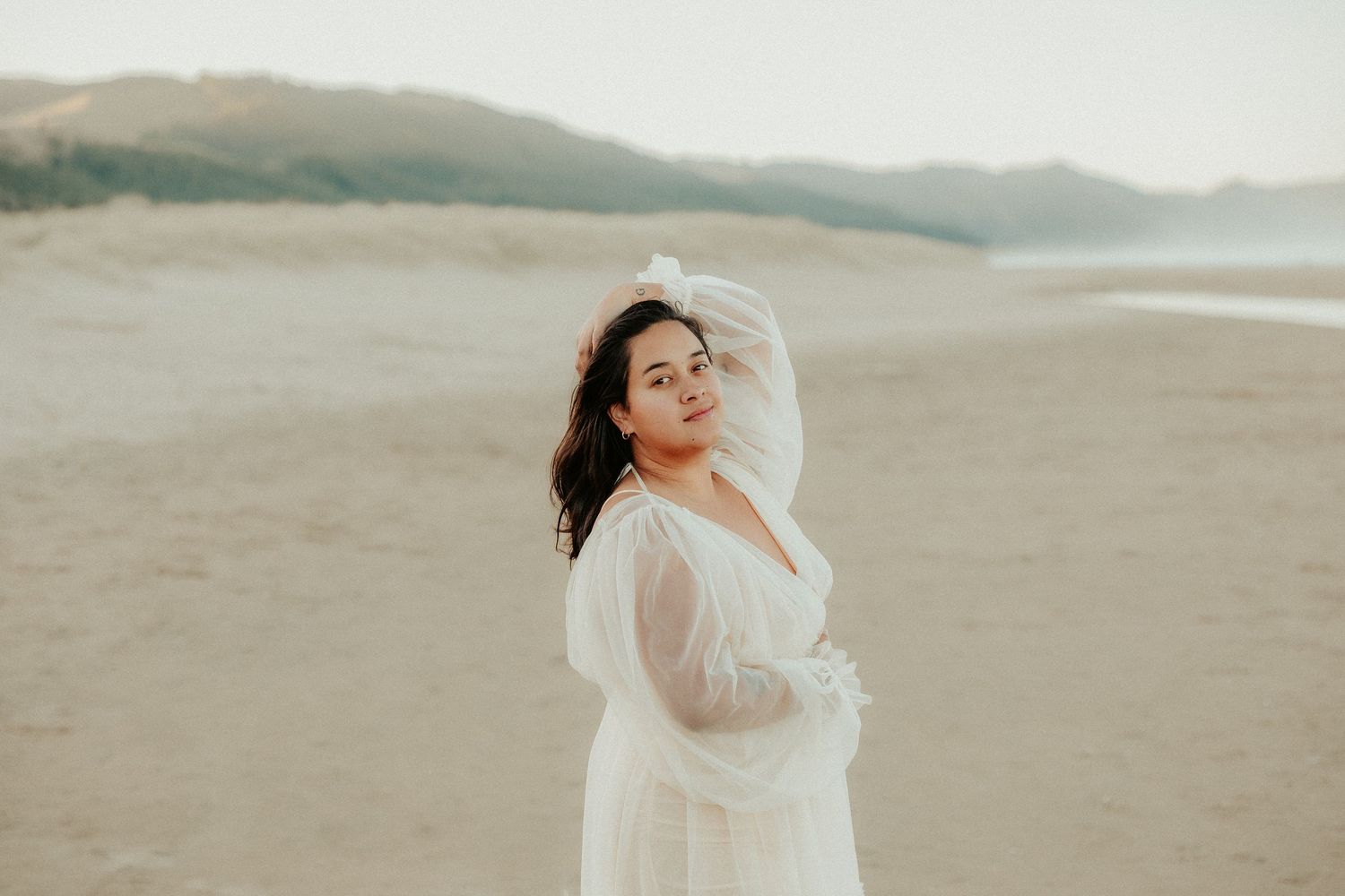 Artistic movement photography of person in white dress against coastal landscape.