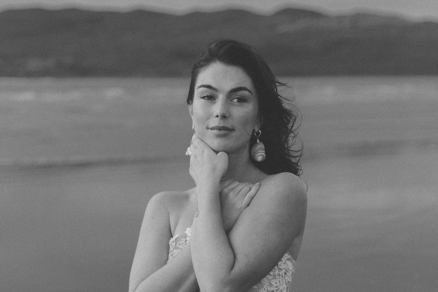 Dramatic black and white beach photography with mountains in the background.