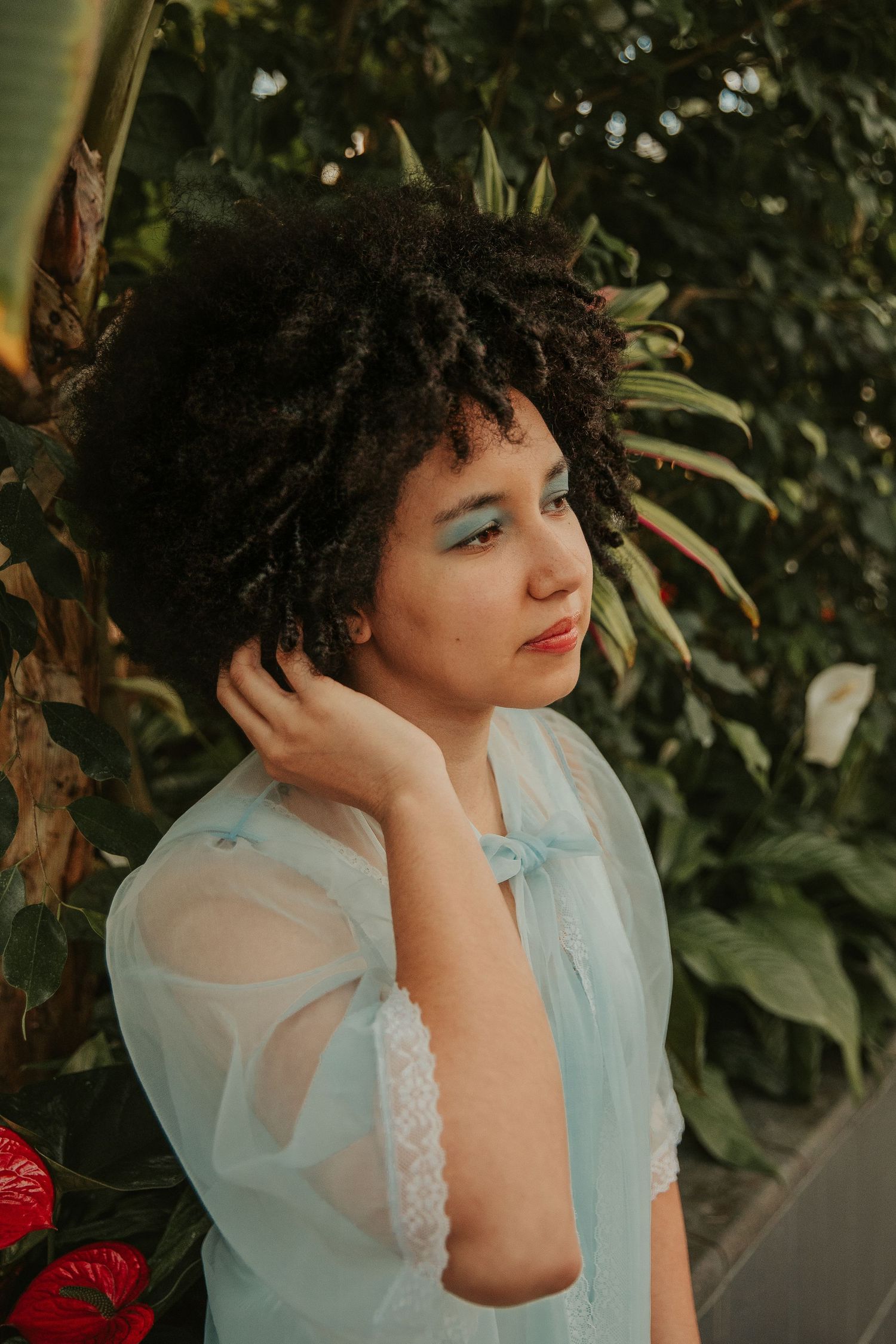 Dreamy portrait in blue vintage dress against lush garden backdrop.
