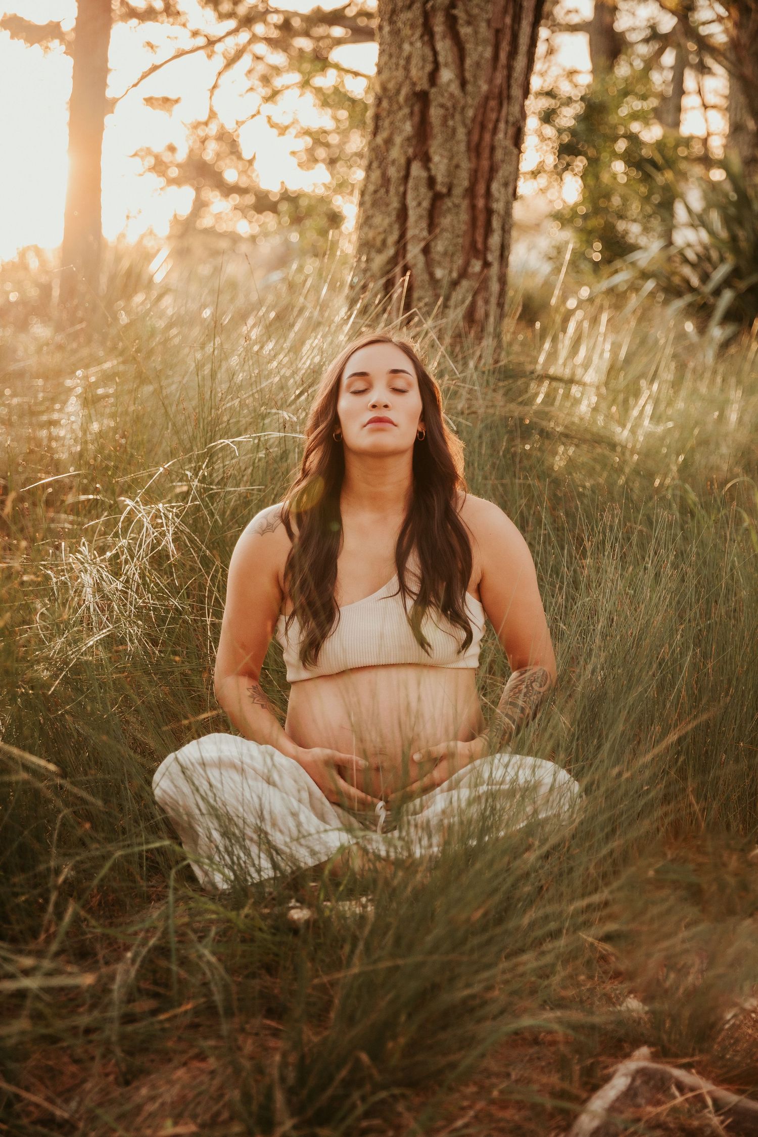 Peaceful outdoor portrait session among tall grass and pine trees at sunset.