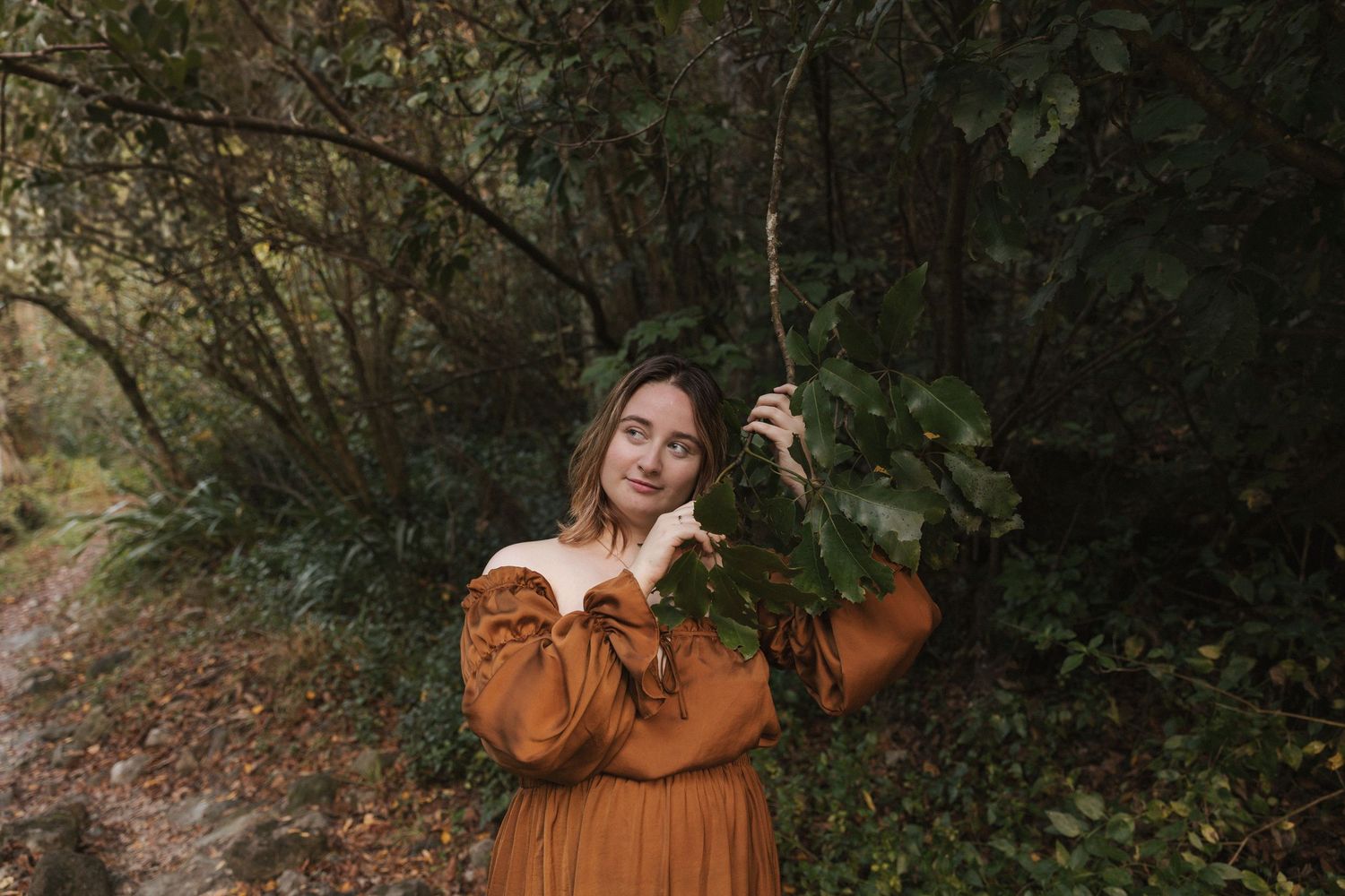 Ethereal woodland photoshoot featuring a flowing brown dress with romantic details.