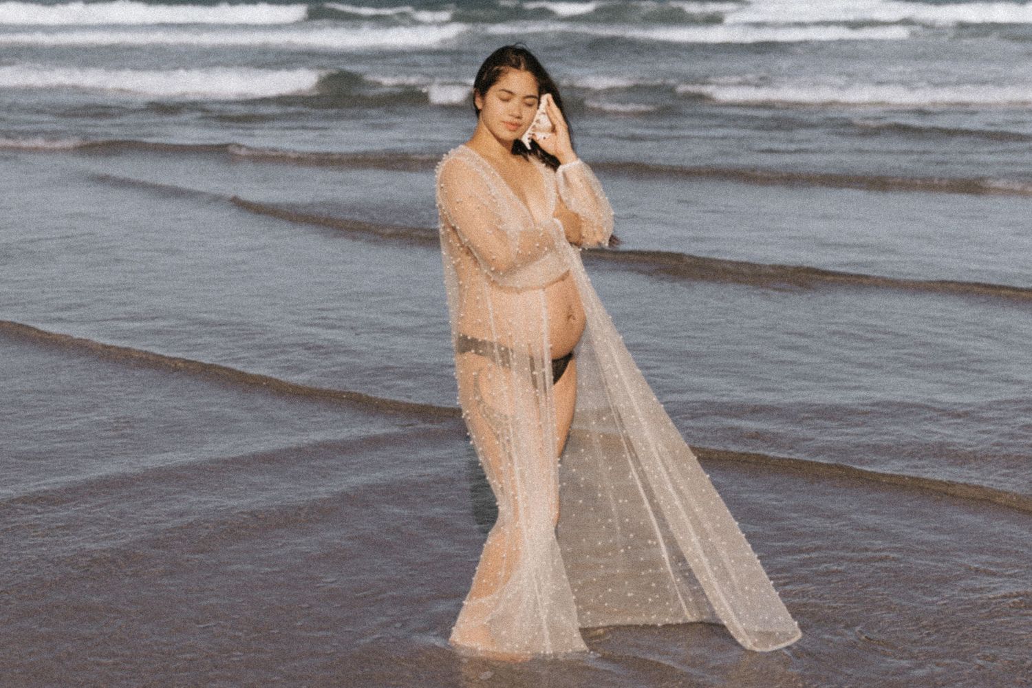 Ethereal beach photoshoot featuring flowing sheer fabric in warm sunlight.