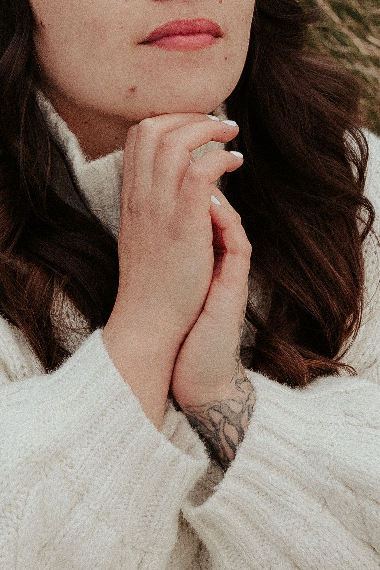 Close-up detail of hands in a cream knit sweater with delicate pose.