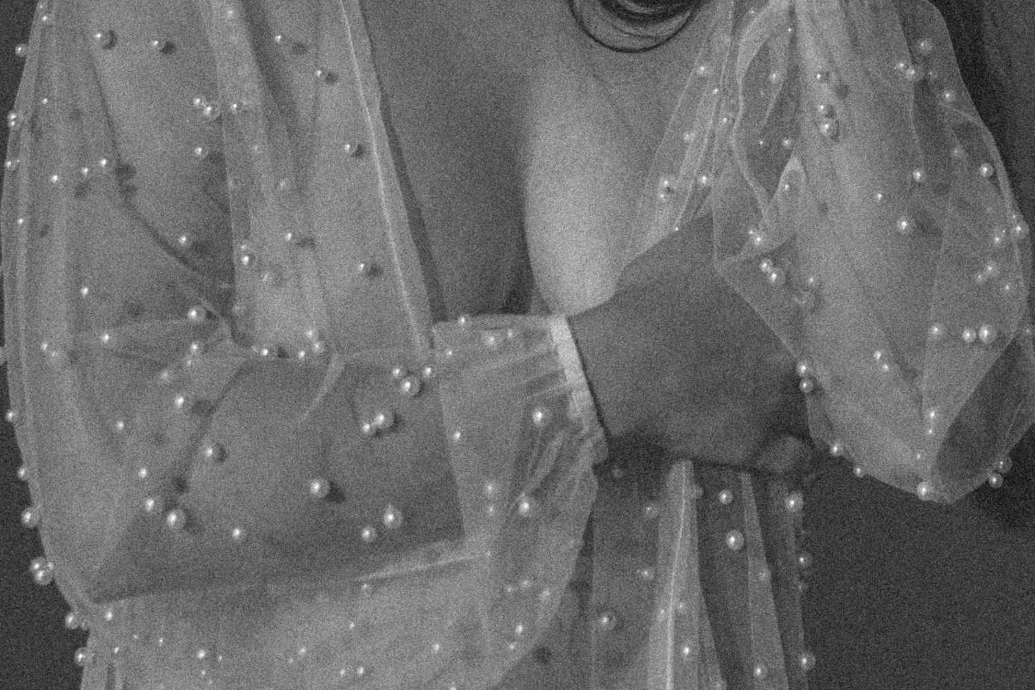 Close-up details of a pearl-embellished sheer fabric in black and white.