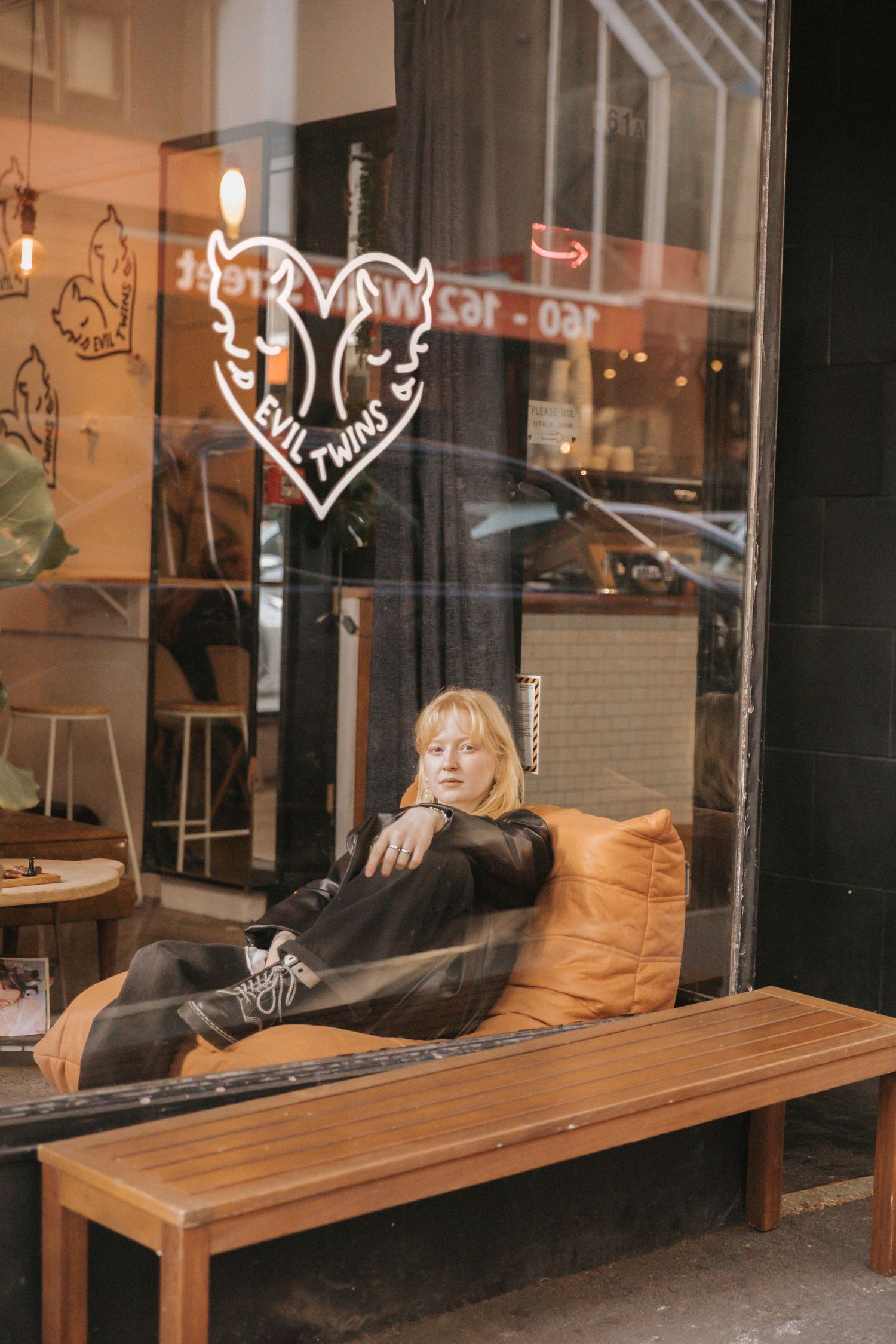 Wooden bench seating outside a storefront with graffiti art on windows.
