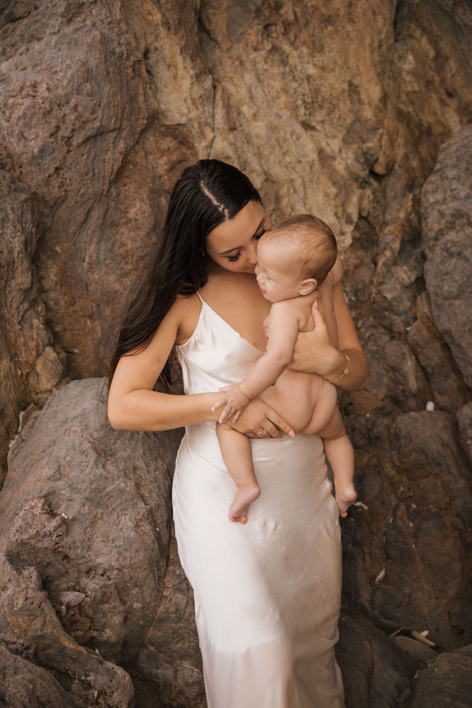 Emotional photography session featuring soft white fabric against rough stone textures.