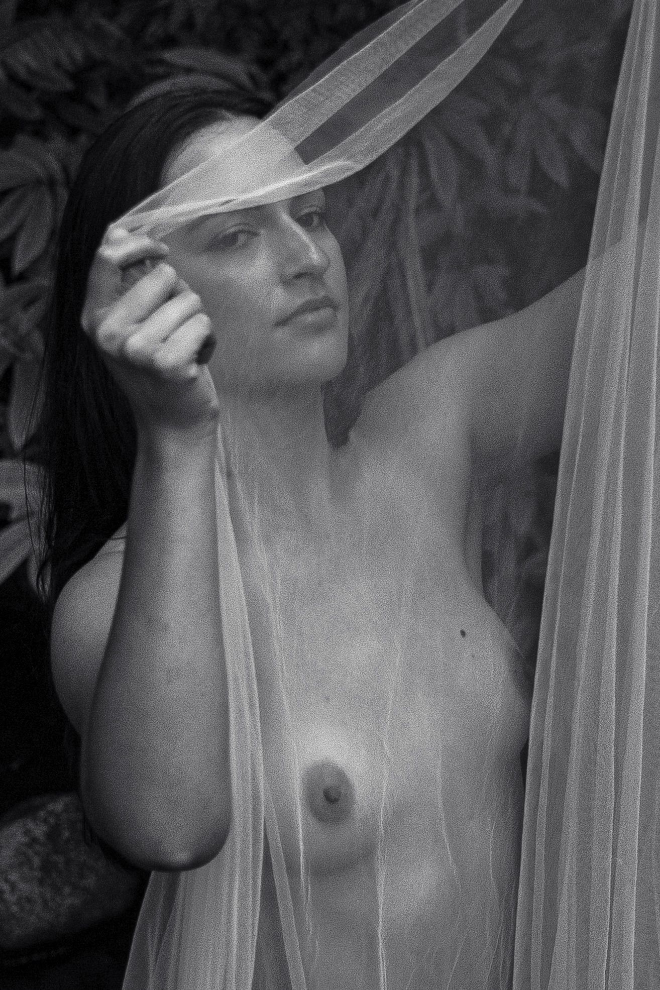 Black and white artistic portrait with delicate veil creating dramatic shadows.