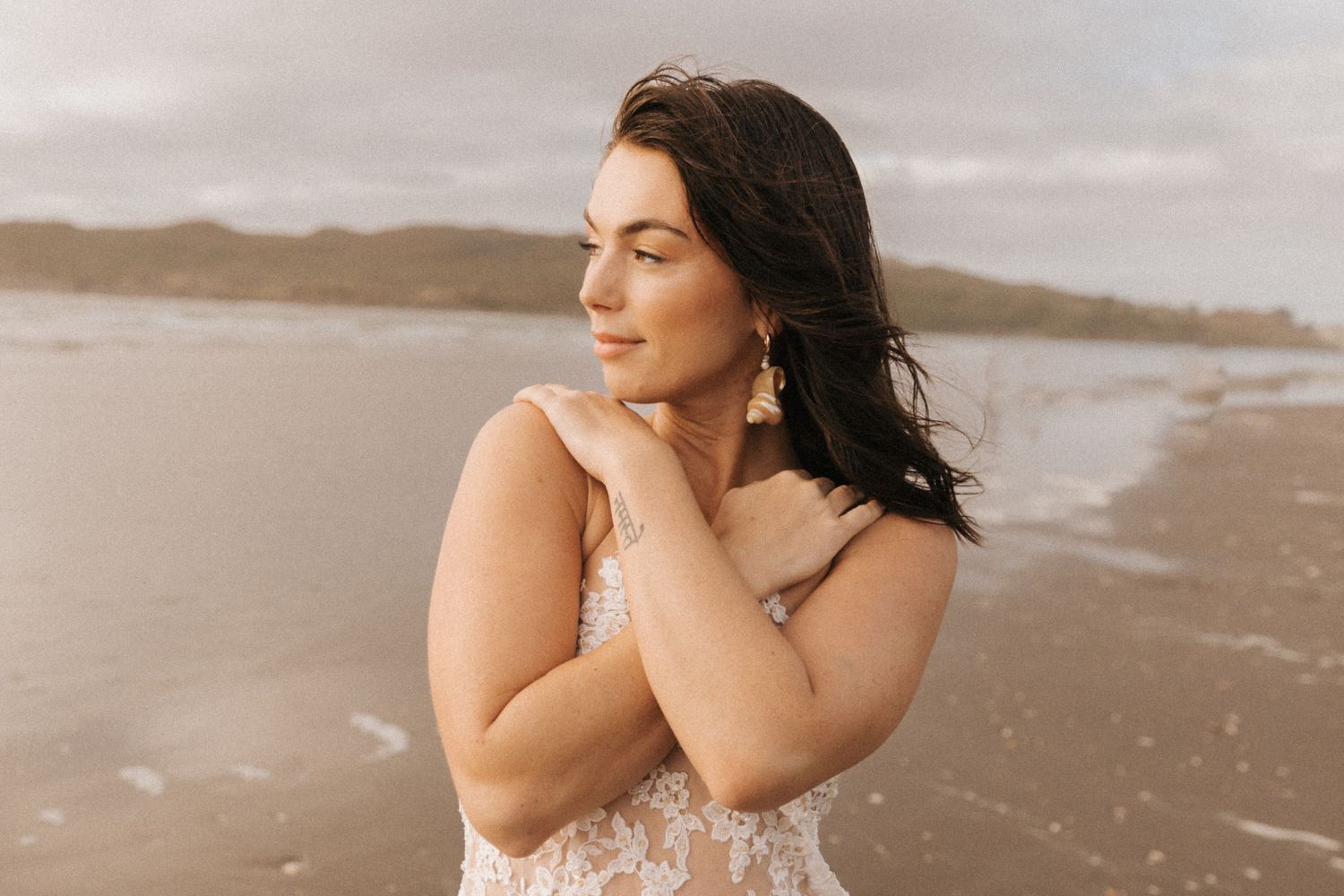 Elegant beachside portrait with lace gown against moody coastal backdrop.