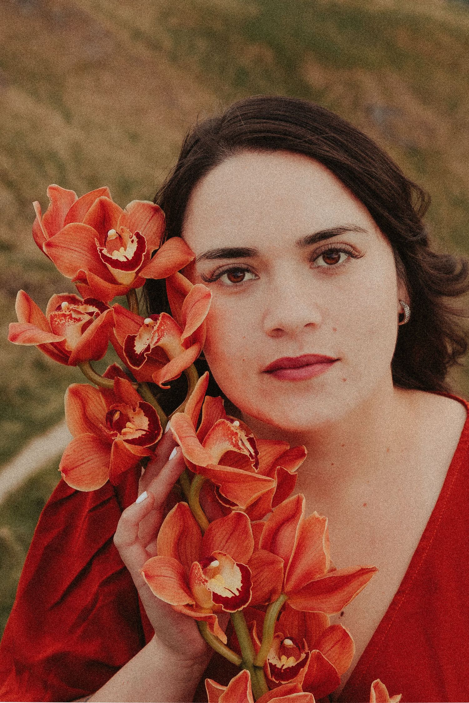 Close-up portrait with vibrant orange orchids and red clothing.