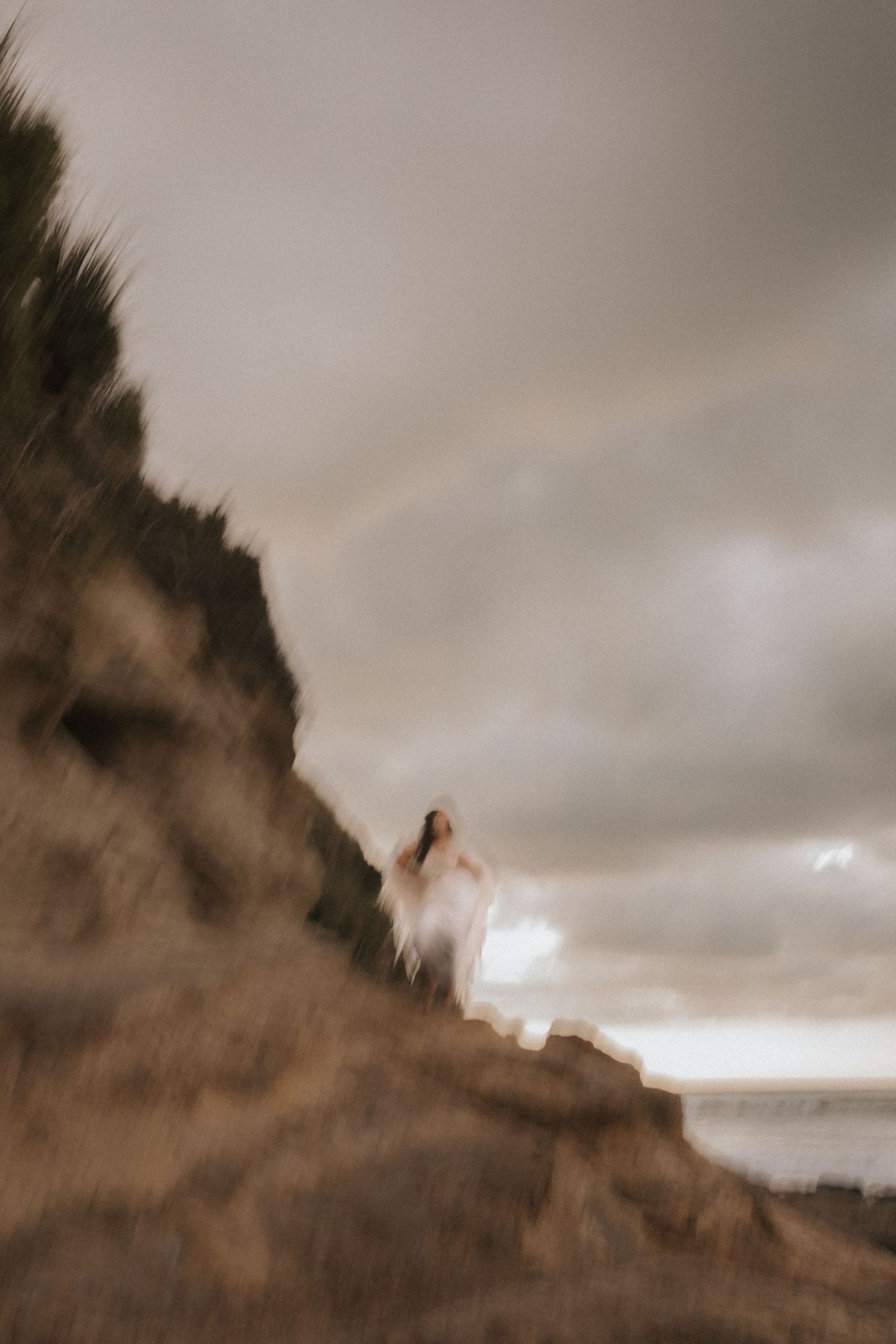 A dramatic sepia-toned panoramic view of a rugged coastal cliff against moody cloudy skies.