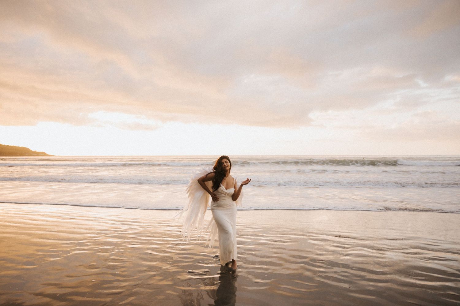 A tranquil sunset beach scene with silhouetted figures walking along the shore as waves roll in during golden hour.