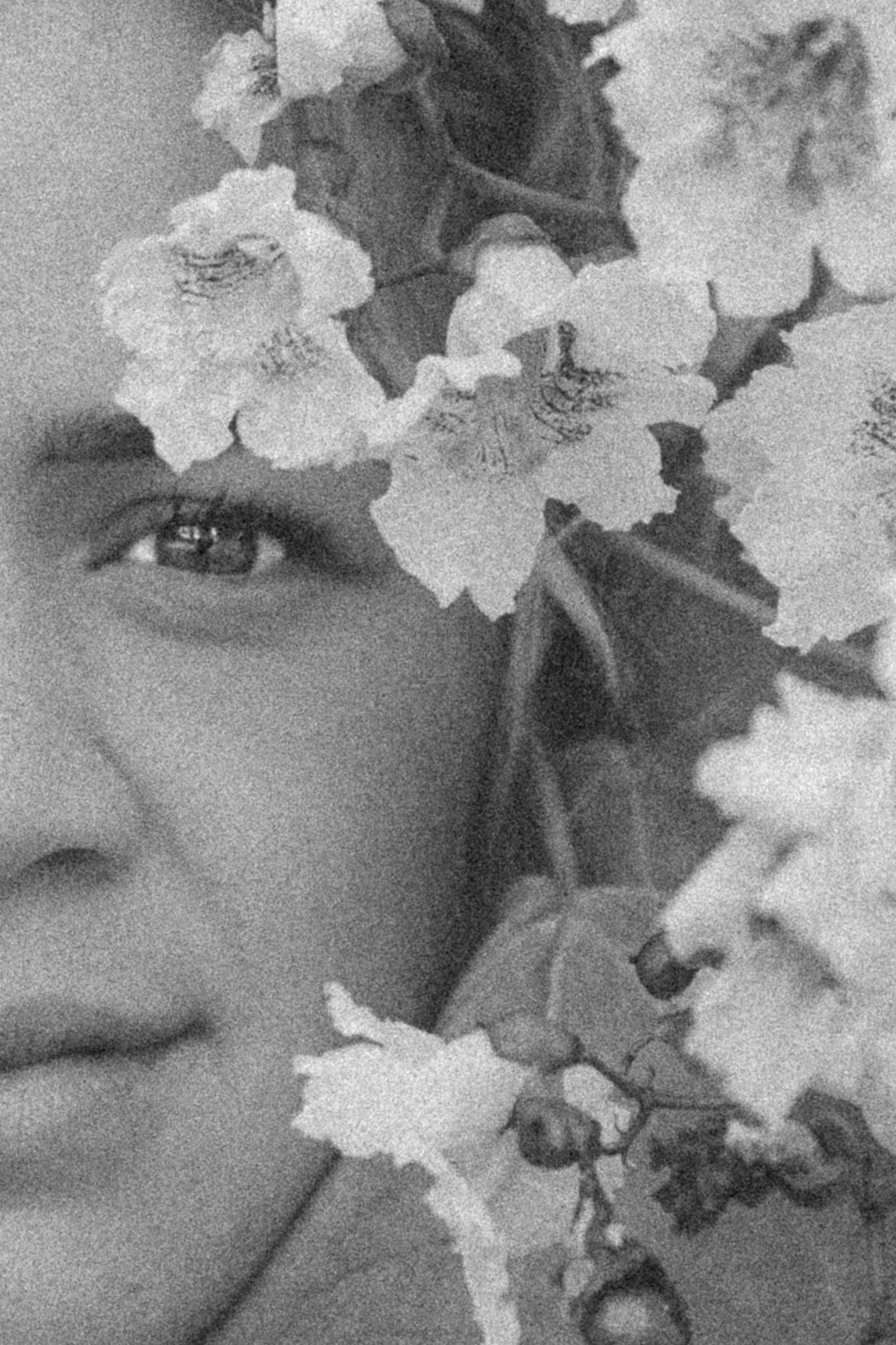 Artistic black and white portrait partially obscured by delicate white flowers.