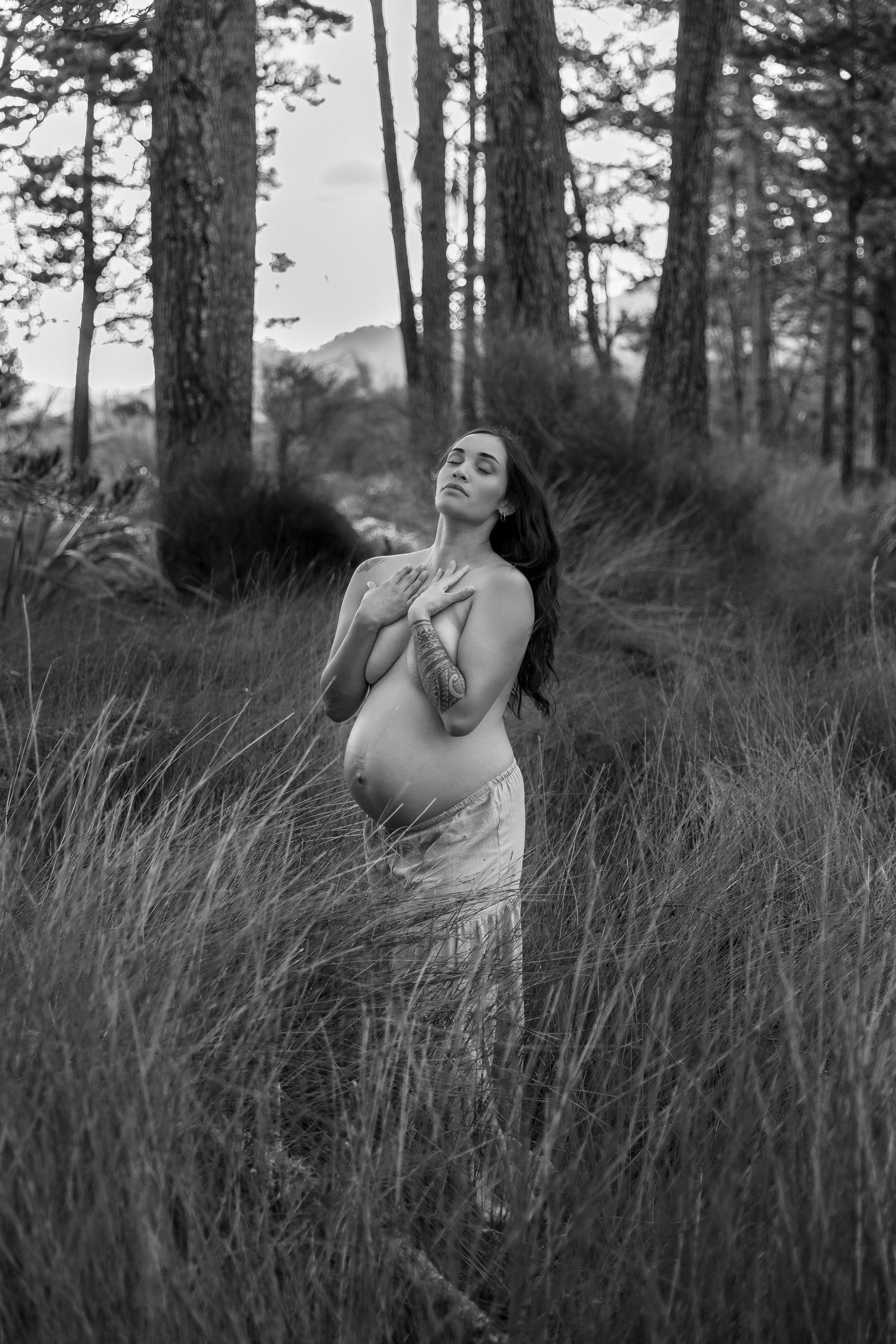 Black and white artistic portrait in a forest setting with dramatic shadows.