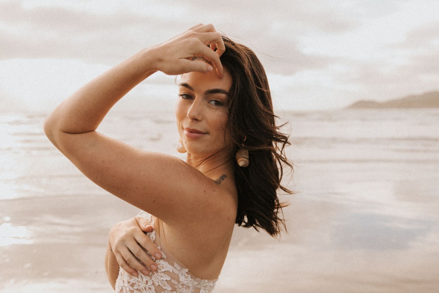 Intimate beach portrait with soft lighting and delicate lace dress details.